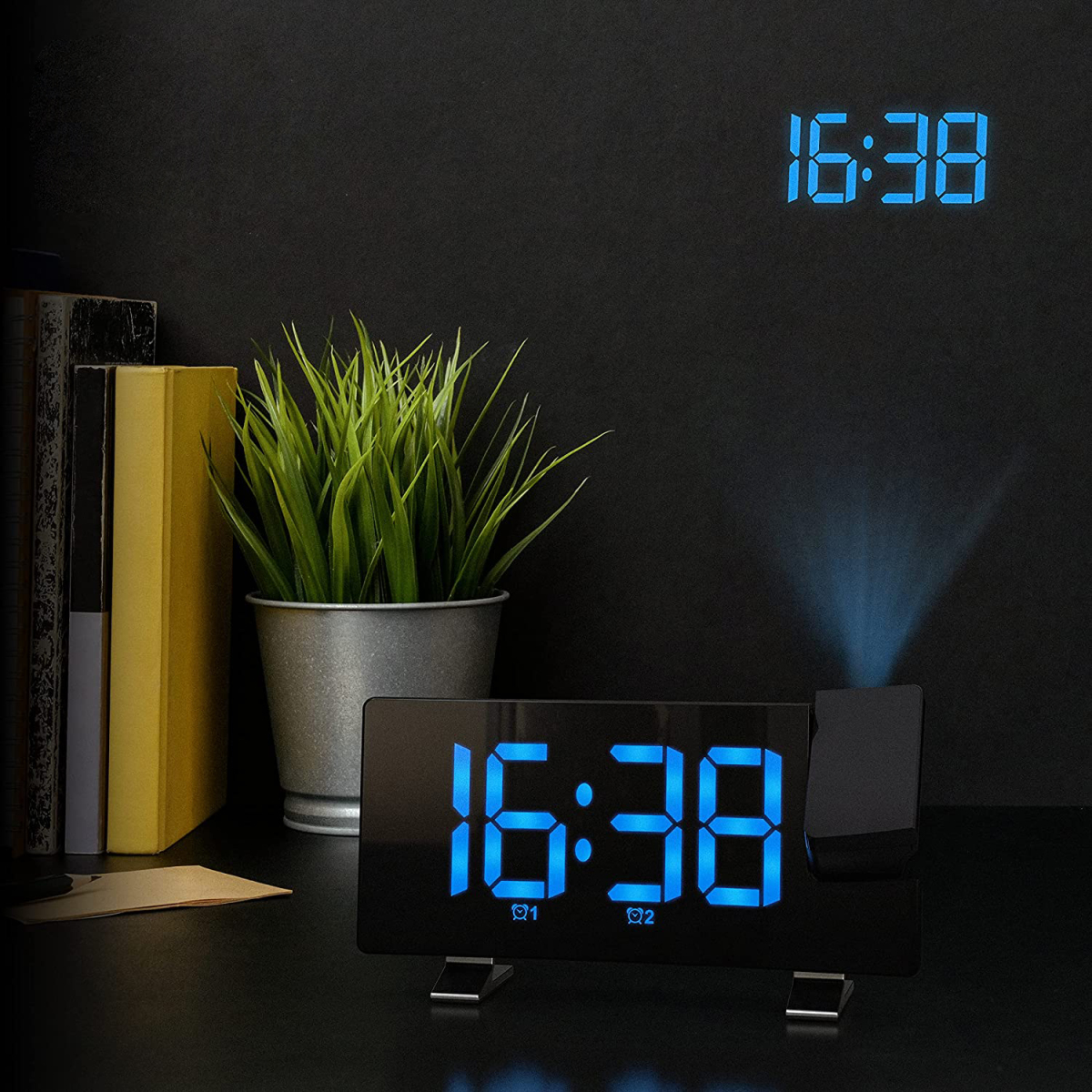 Digitaler Wecker mit 16:38. Eine zweite Uhr projiziert die Zeit an die Wand. Grüne Pflanze im Hintergrund.