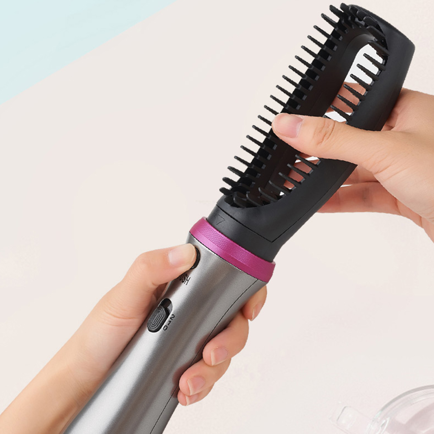 Mani che tengono una spazzola per capelli nera con accento rosa, primo piano.