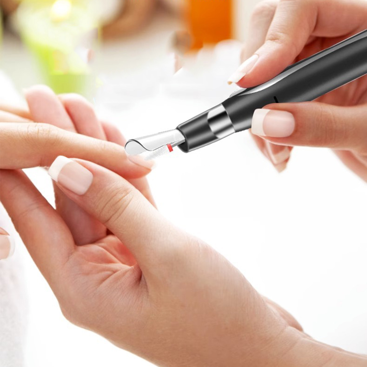 Eine Maniküristin verwendet einen Nagelfräser an den Fingernägeln einer Kundin. Das Werkzeug ist schwarz und silber.