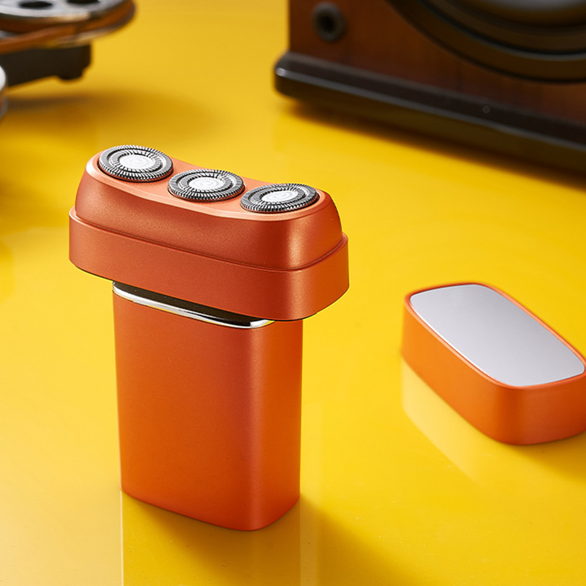 Oranger Elektrorasierer auf gelber Oberfläche.