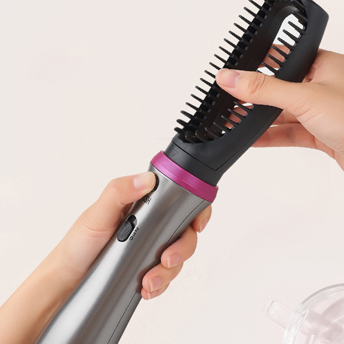 Hand, die eine Haarbürste mit Knopf hält.