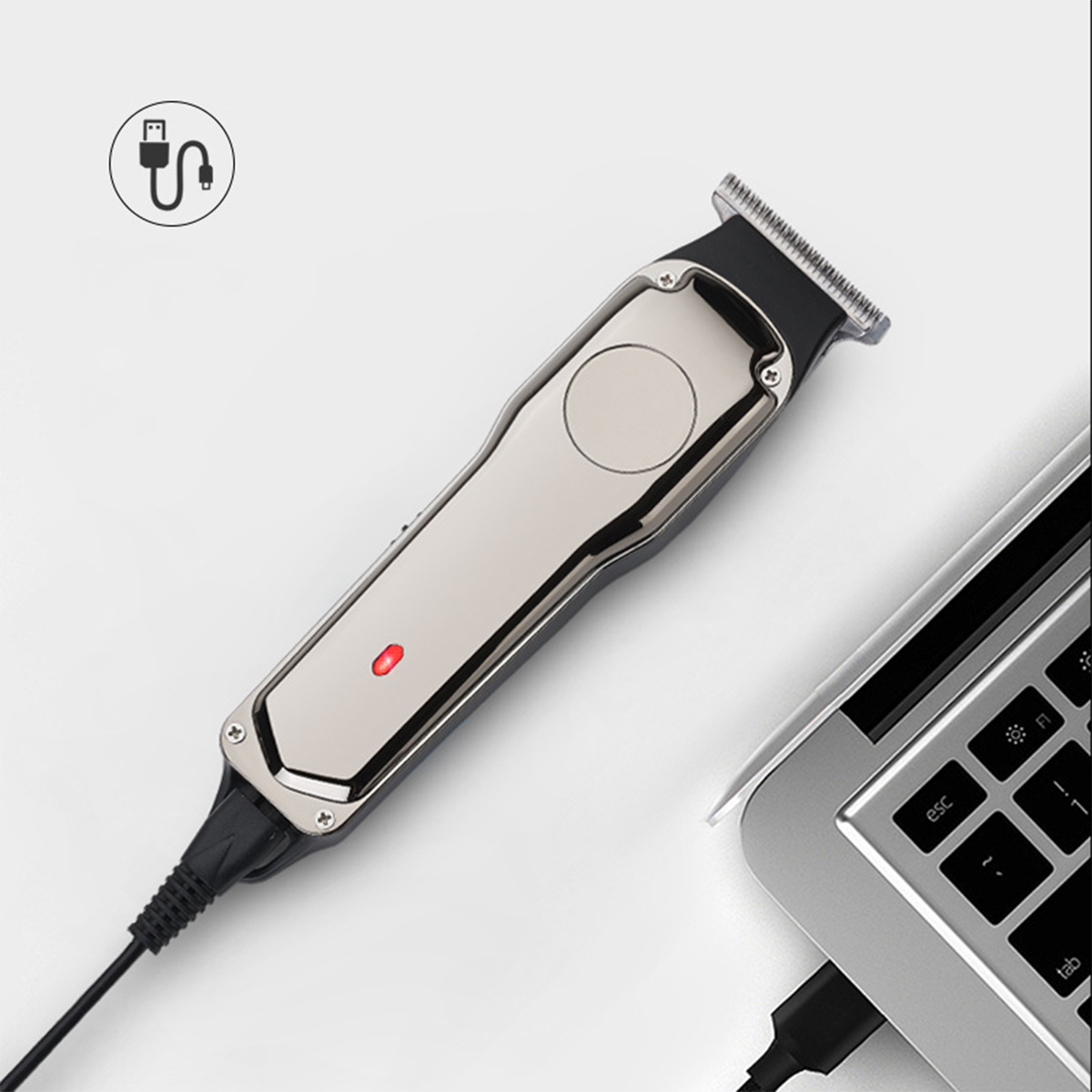 Silberner und schwarzer Haarschneider, der mit einem Ladekabel an einen Laptop angeschlossen ist.
