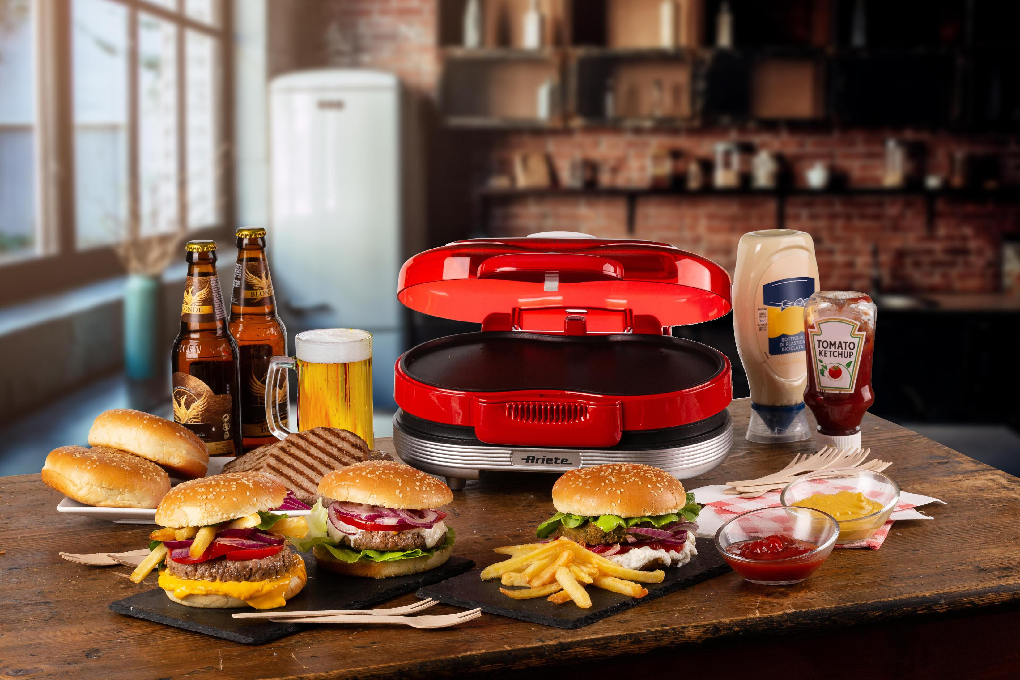 Ein roter Burger Maker mit Burgern, Brötchen, Bier und Gewürzen auf einem Holztisch.