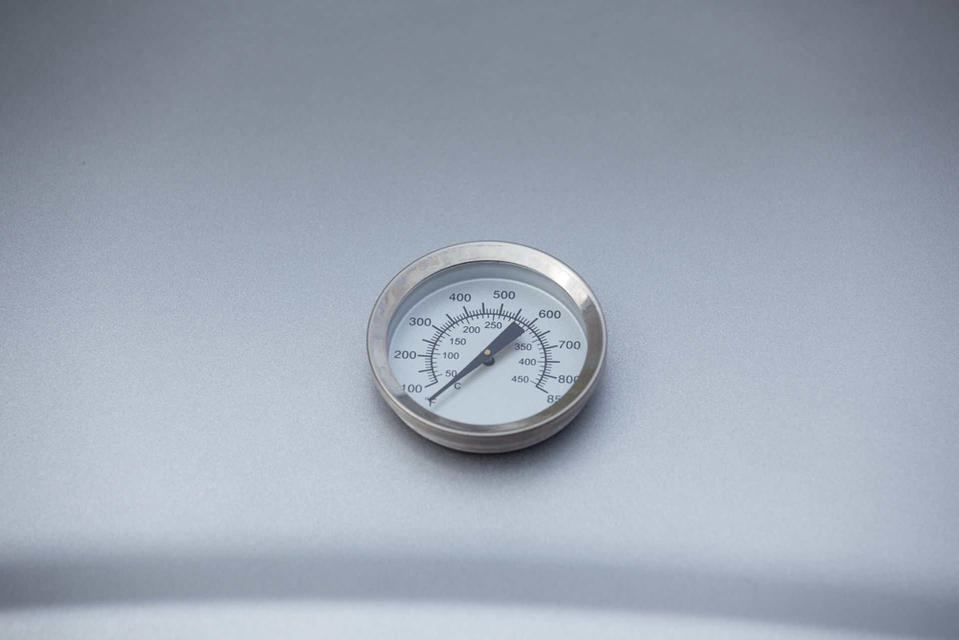 Ein silbernes Thermometer auf grauer Oberfläche mit Temperaturanzeige.