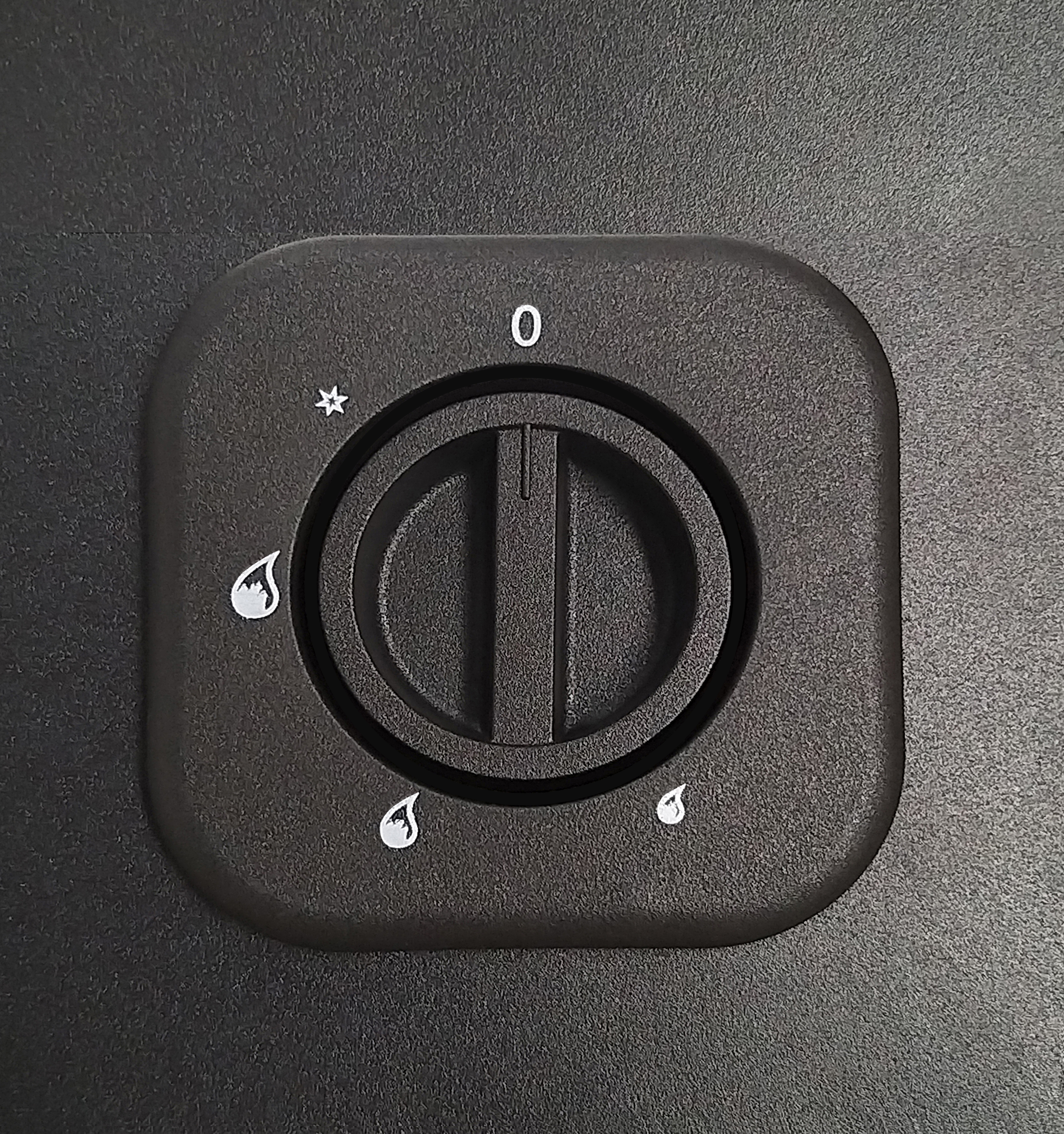Primer plano de un dial negro de un electrodoméstico con símbolos y números.