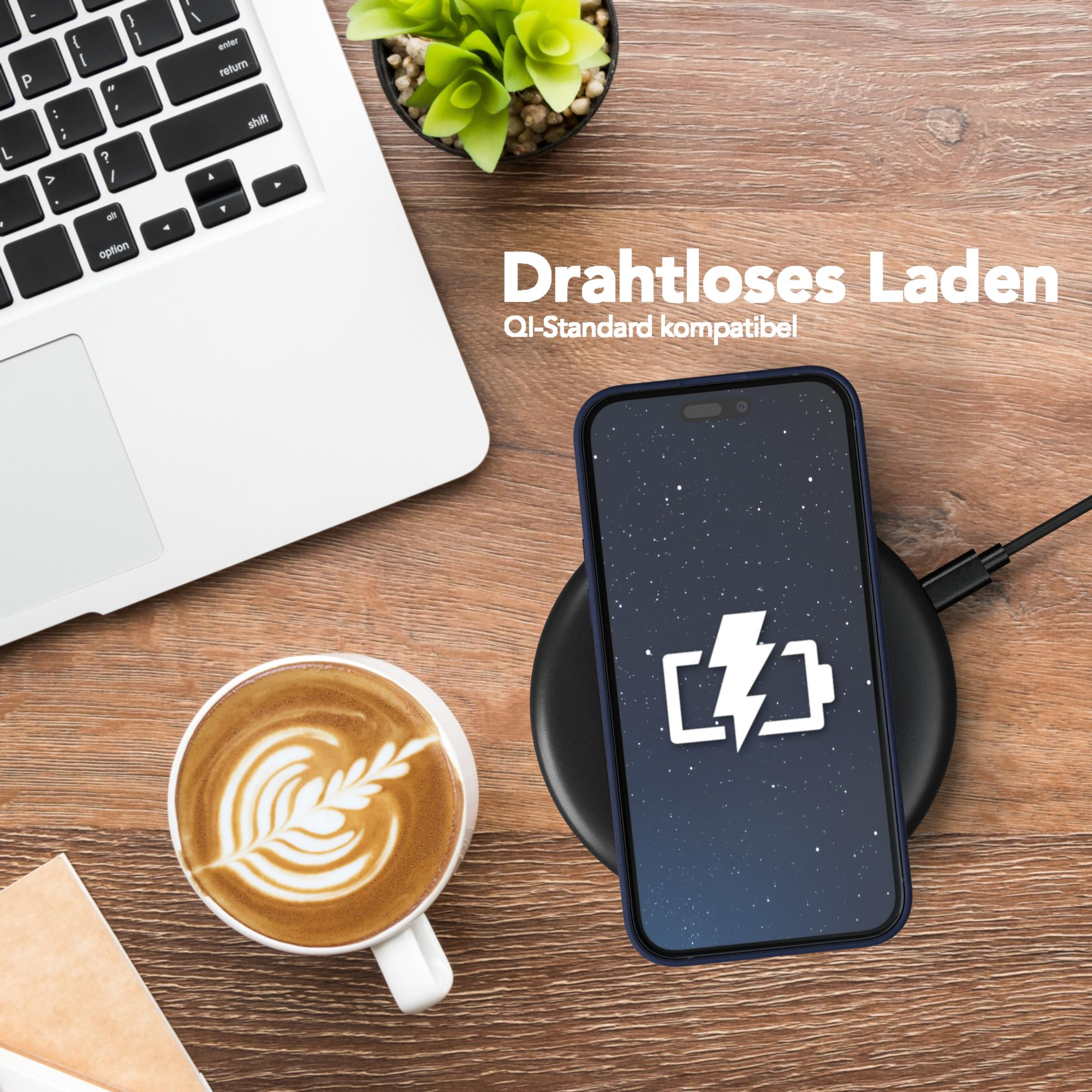 Laptop, Kaffeetasse und Telefon, das kabellos auf einer dunklen Oberfläche geladen wird.