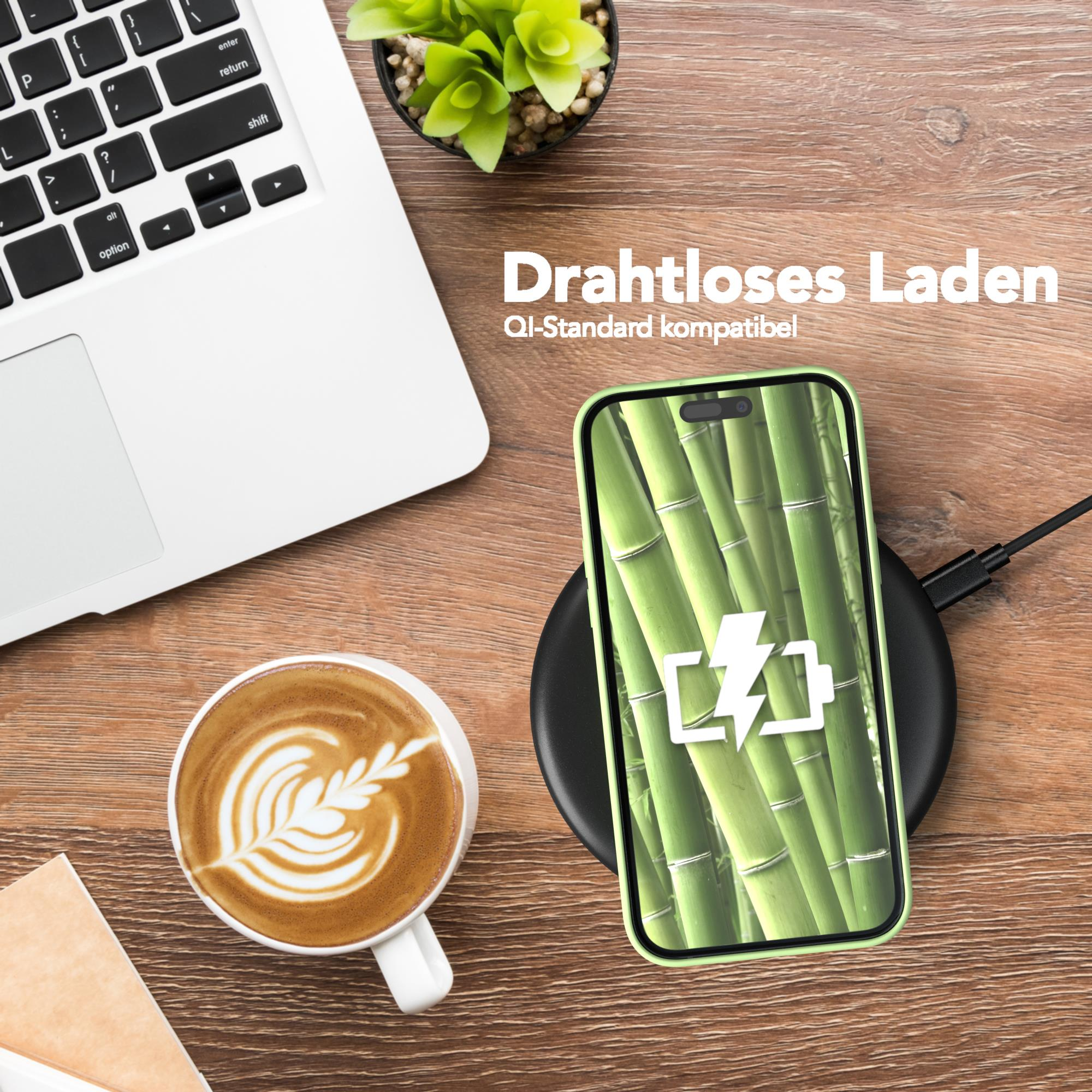 Ein Telefon auf einem kabellosen Ladegerät mit einer Kaffeetasse und einer Pflanze. Das Telefon zeigt einen Bambushintergrund.