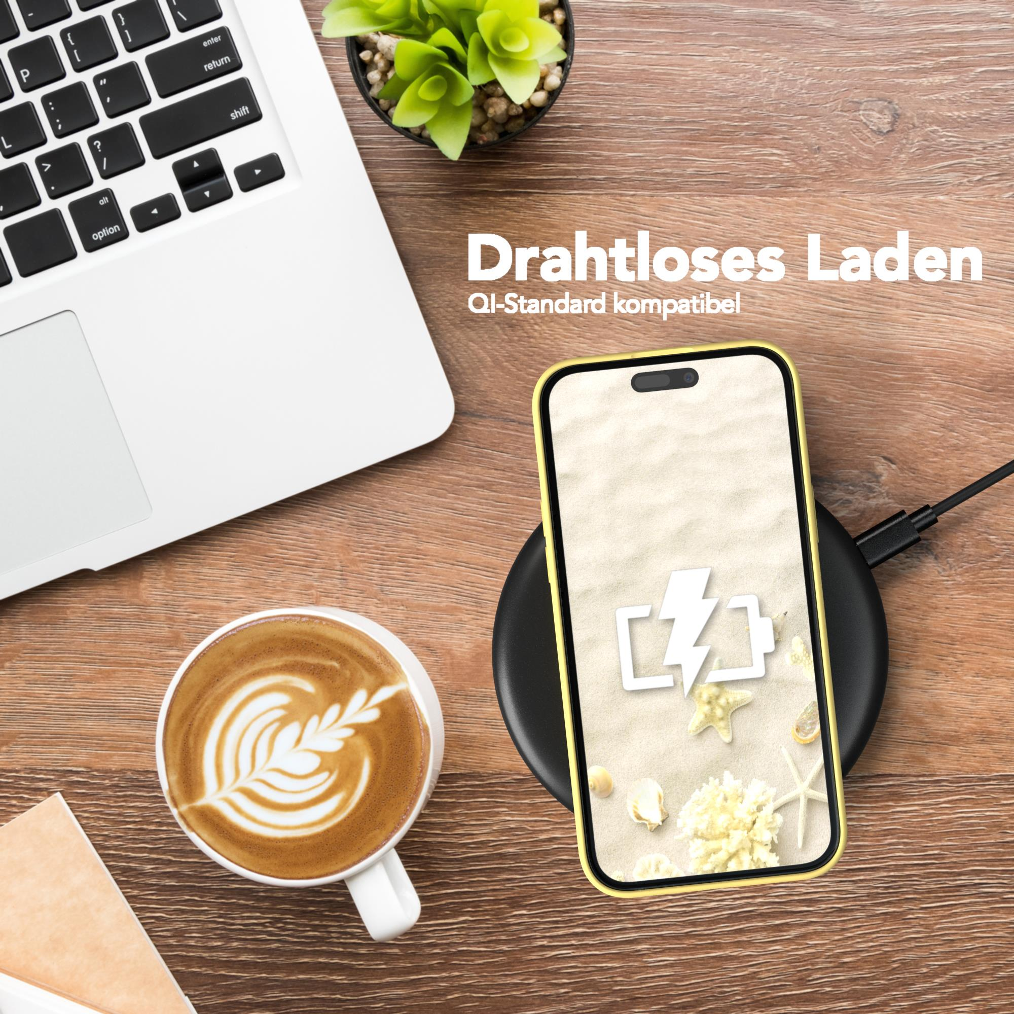 Ein Telefon liegt auf einem kabellosen Ladepad, mit einer Kaffeetasse und einem Laptop in der Nähe.