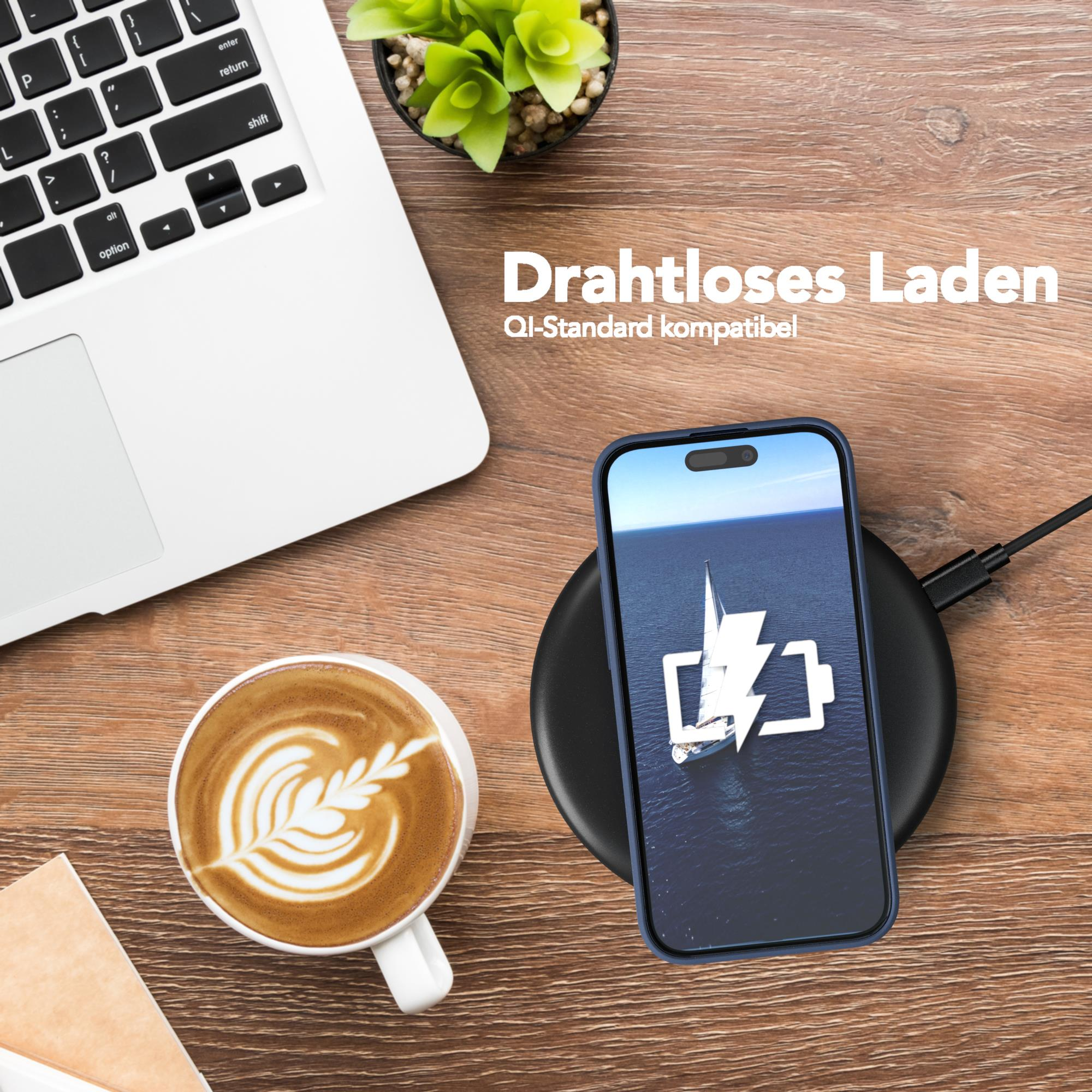 Ein Telefon, das drahtlos auf einem schwarzen Pad geladen wird, neben einem Laptop und einer Kaffeetasse mit Latte Art.