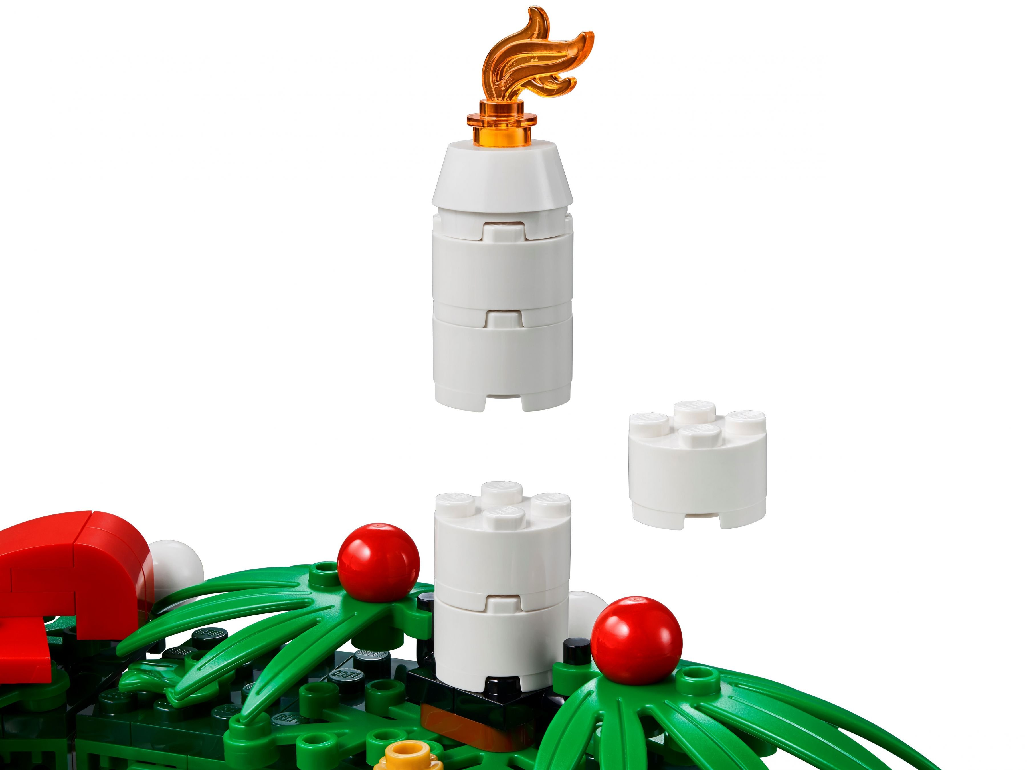 Alevli beyaz Lego mum. Alt kısımda yeşil ve kırmızı Lego öğeleri. Beyaz arka plan.