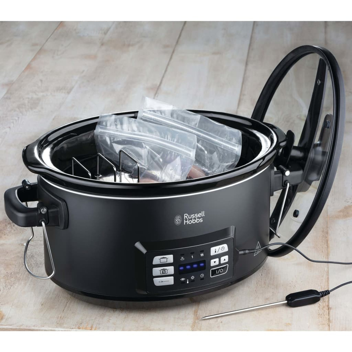 Schwarzer Slow Cooker mit Deckel, mit zwei Beuteln und Bedienfeld.