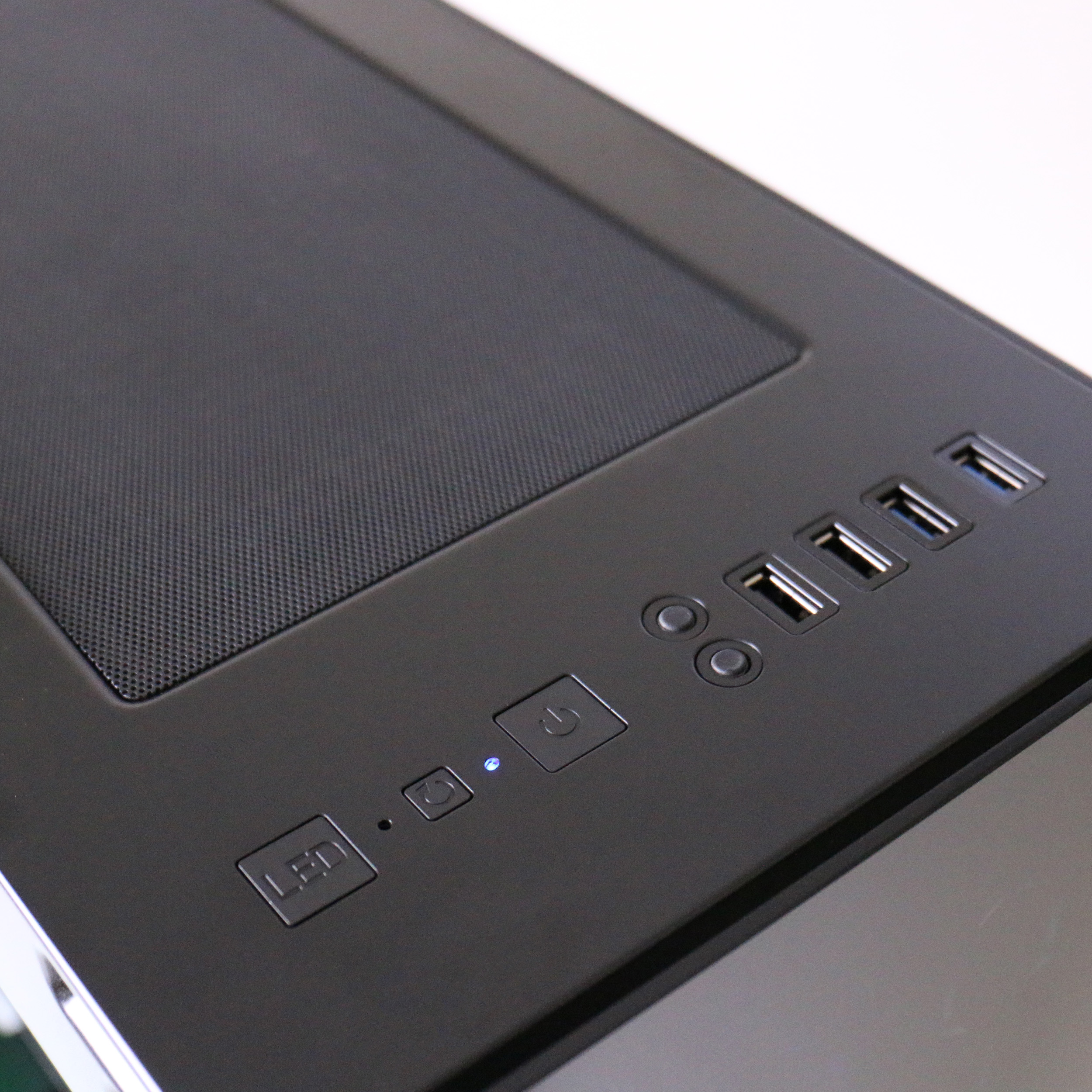 Nahaufnahme eines schwarzen Computergehäuses mit Strom- und USB-Anschlüssen und Tasten.