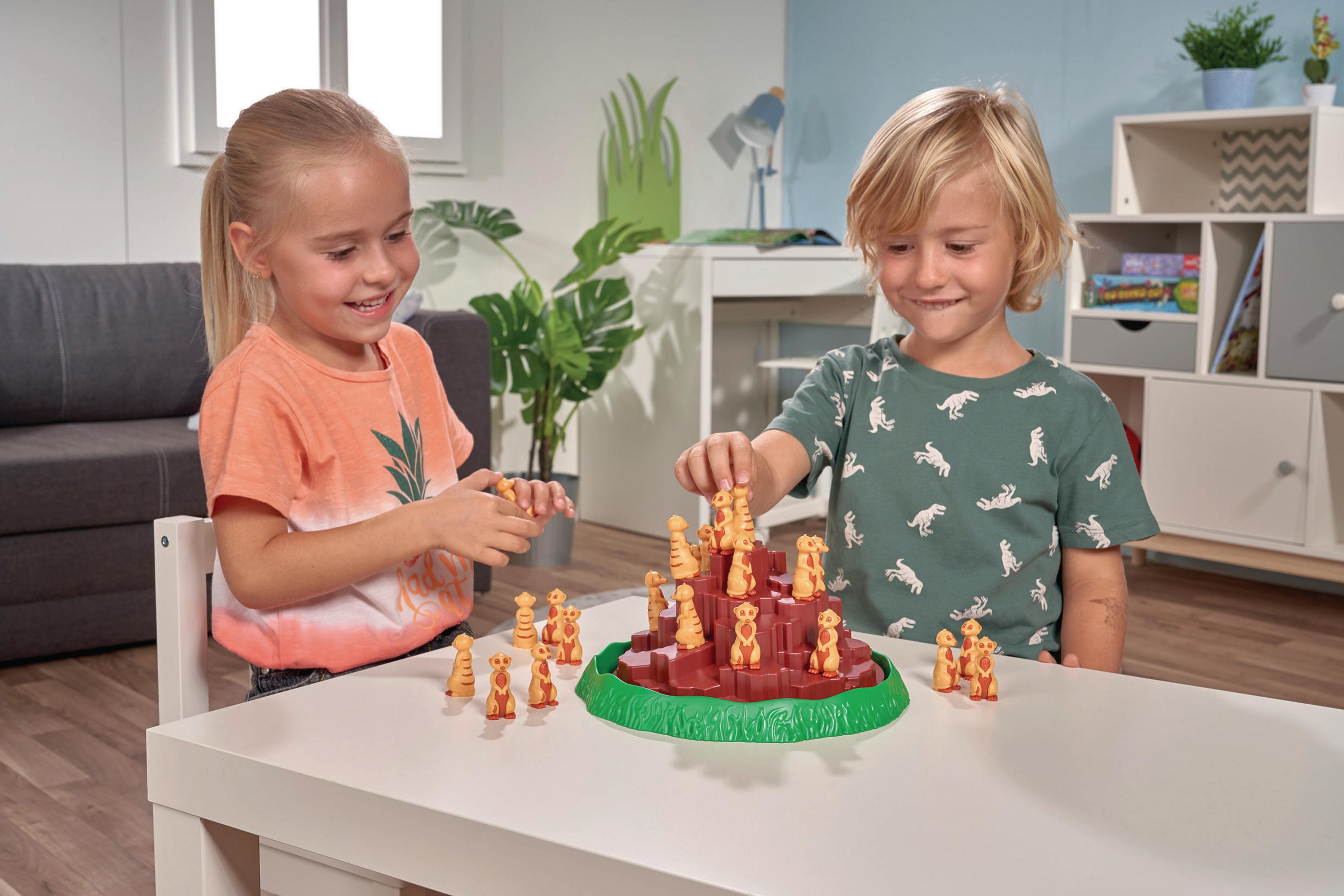 Zwei Kinder spielen ein Erdmännchen-Spiel auf einem Tisch mit weißem Hintergrund.