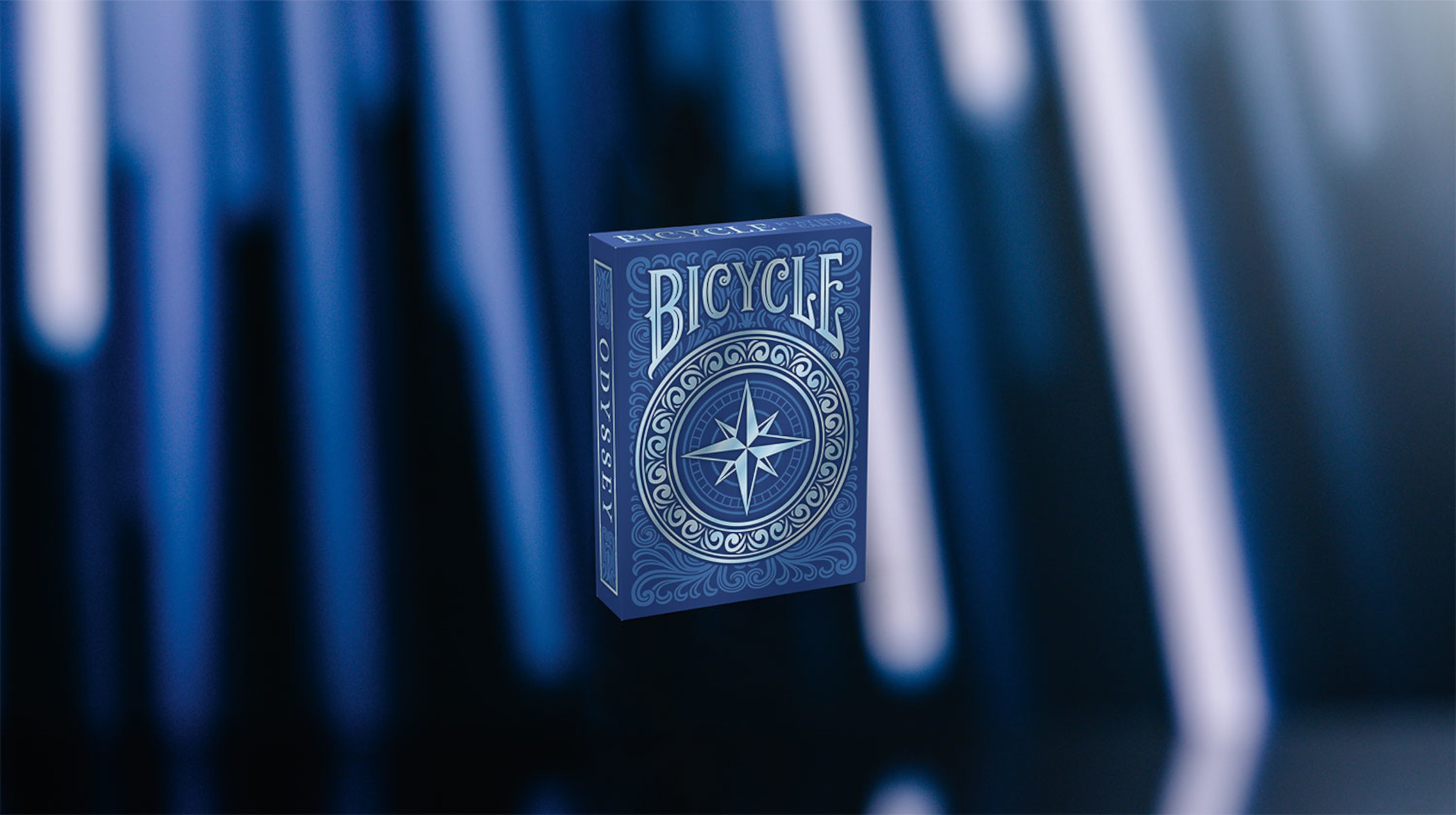 Eine Bicycle Odyssey Spielkartenbox auf verschwommenem blauem Hintergrund.