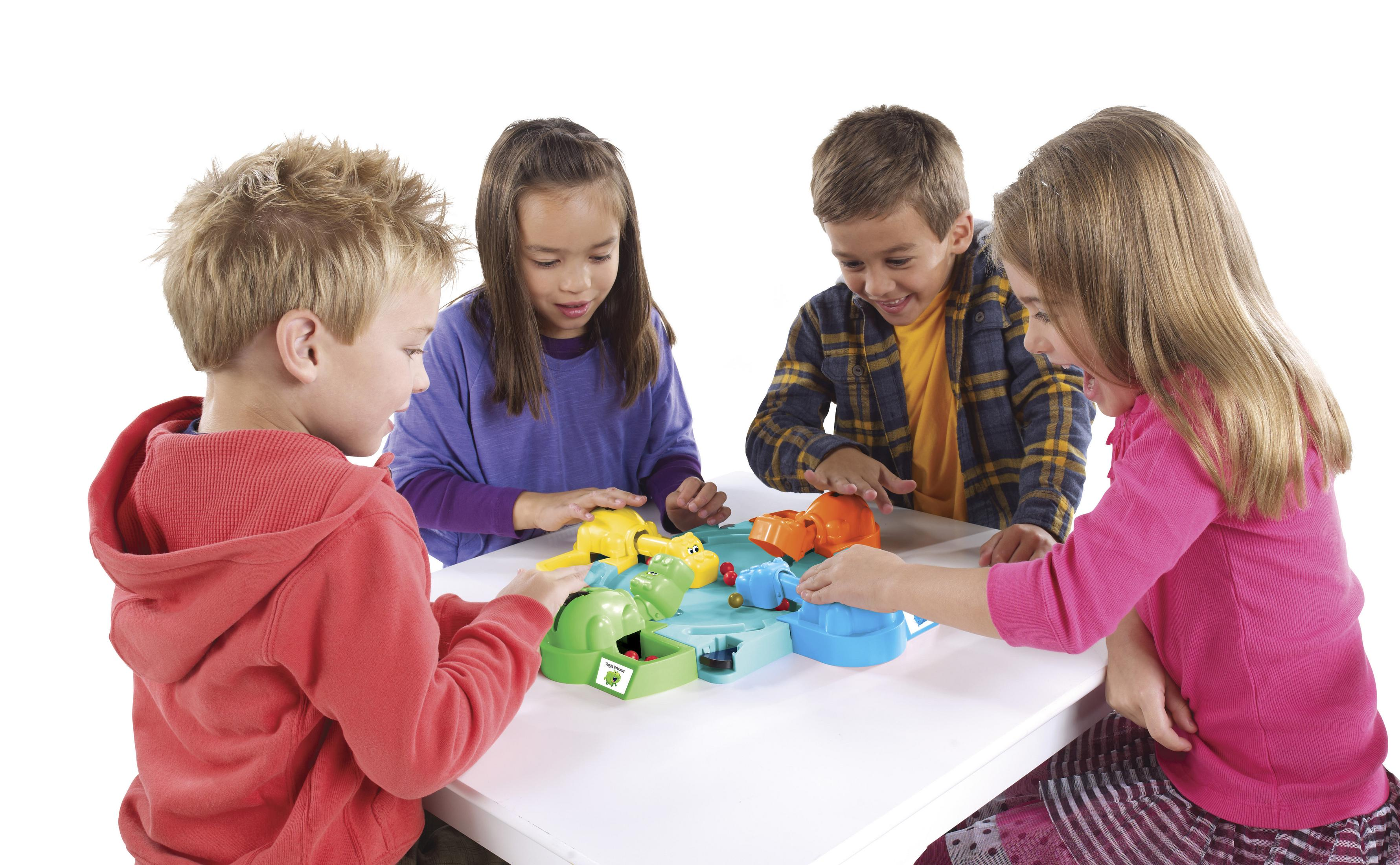 Vier Kinder spielen ein Brettspiel. Das Spiel ist weiß und hat grüne und blaue Teile.