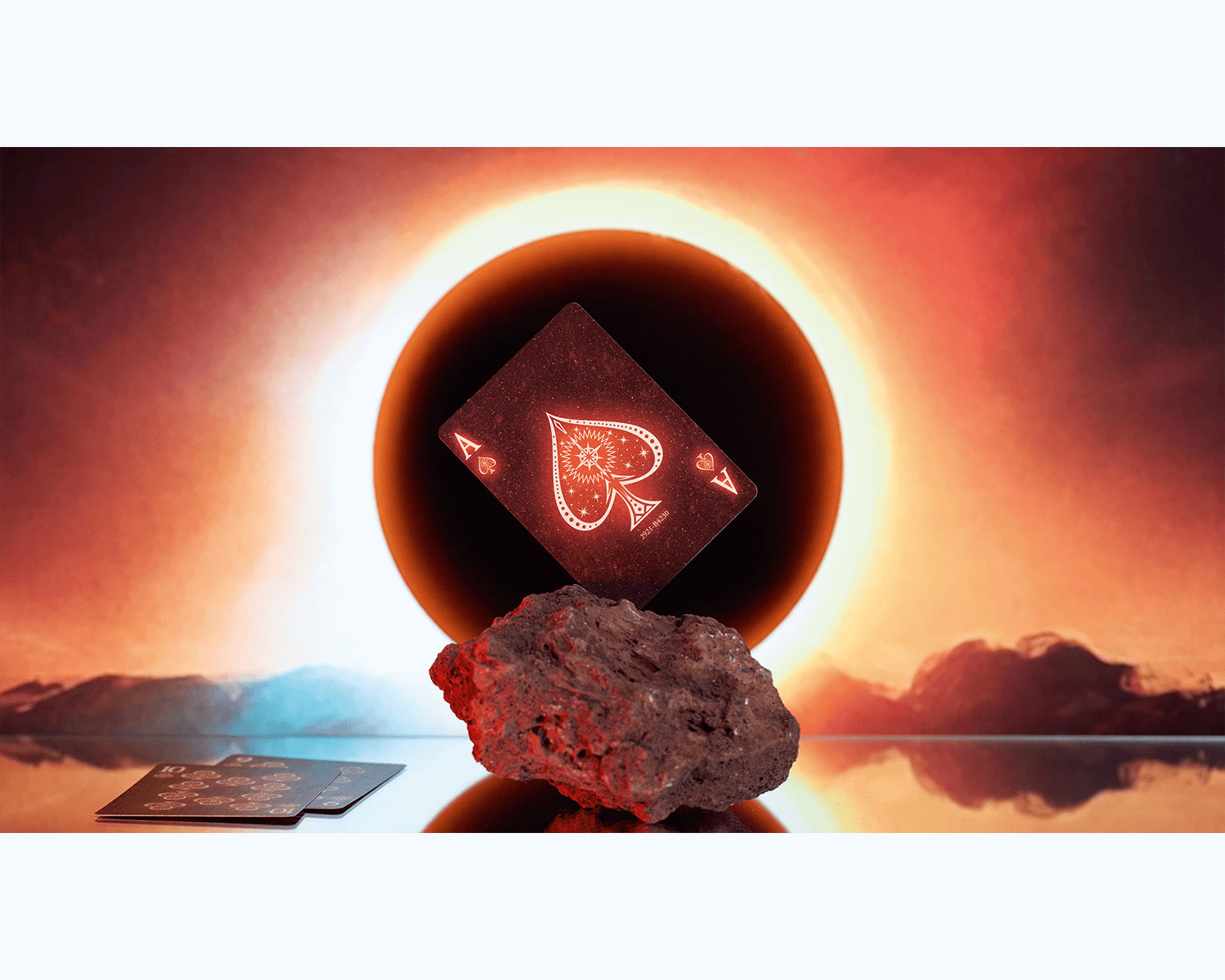 Spielkarte mit Pik-Ass. Sie liegt auf einem Felsen vor einem Sonnenuntergang.