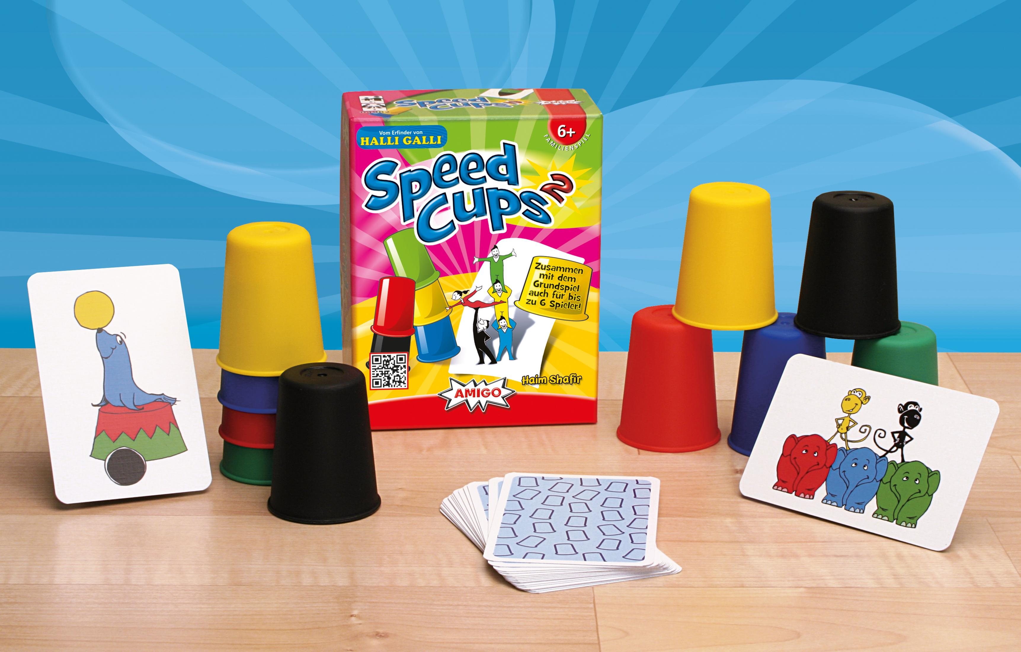 Speed Cups Spiel. Becher, Karten und Schachtel stehen auf einem Holztisch. Verschiedene Farben.