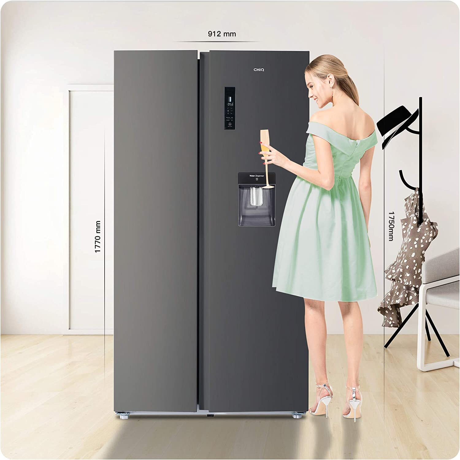 Una mujer con un vestido verde está de pie junto a un gran refrigerador negro. La nevera tiene dimensiones marcadas.