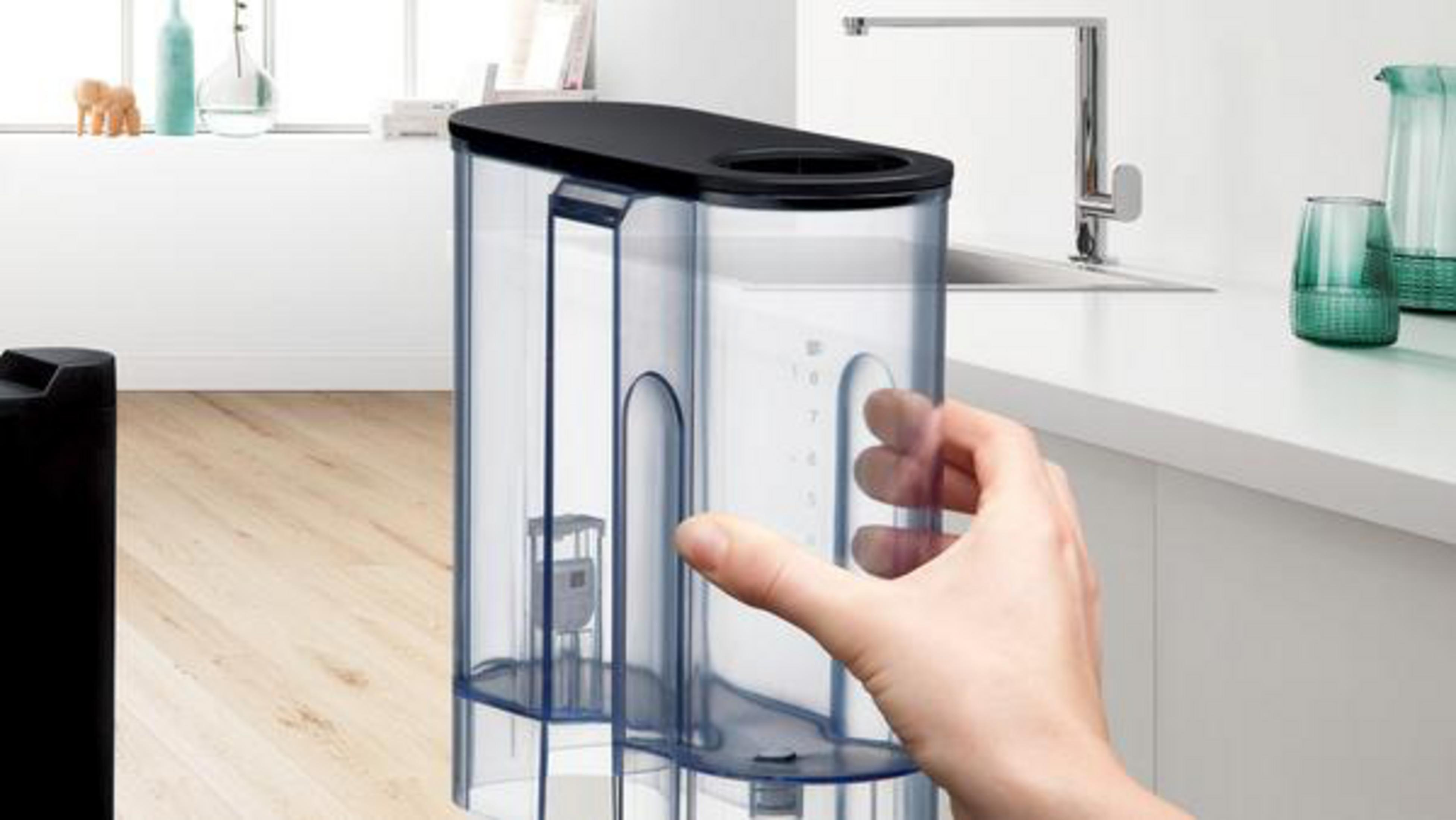 Ręka trzyma przezroczysty zbiornik na wodę z czarną pokrywą.