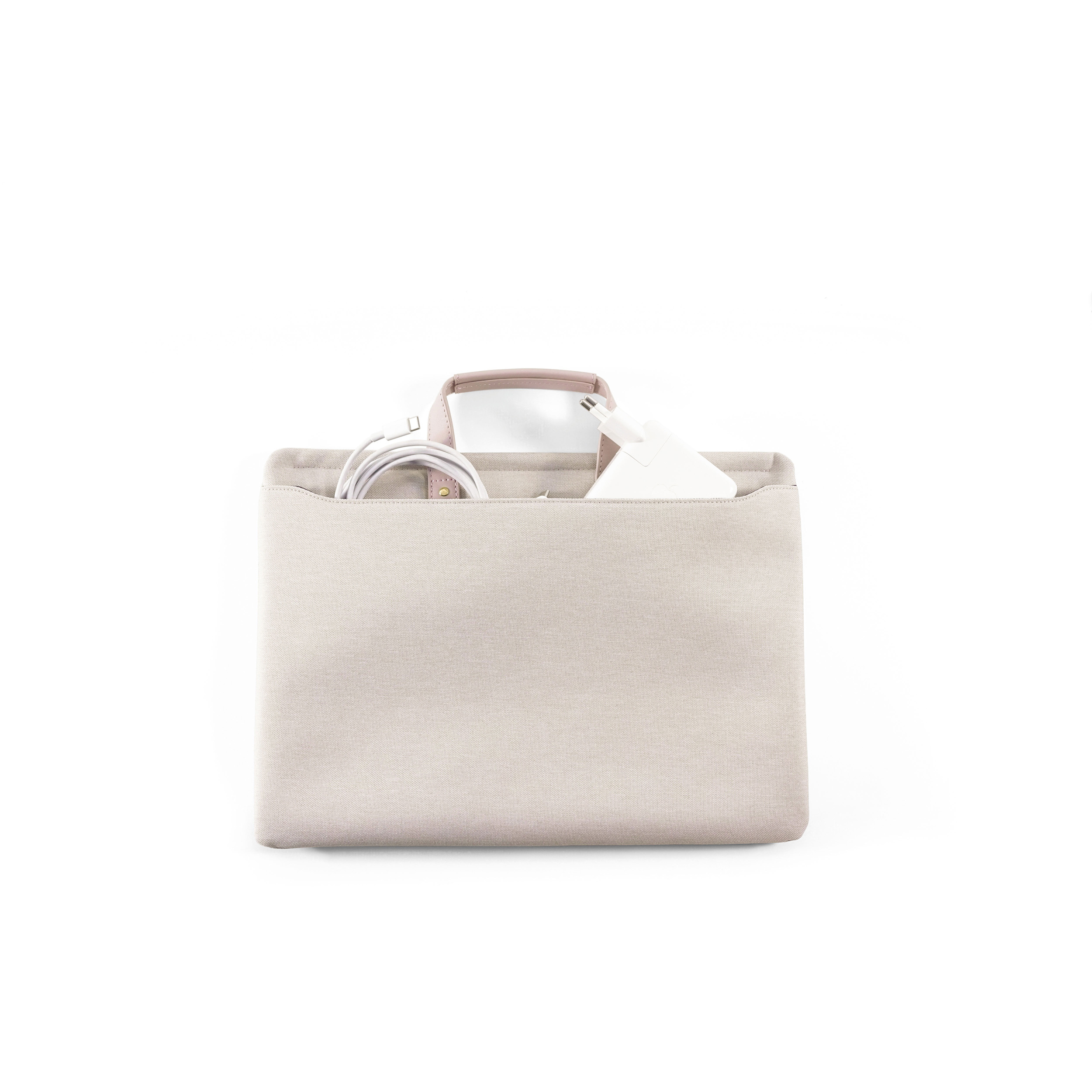 Eine beige Tasche mit Griff, enthaltend weiße Kabel und ein Netzteil auf weißem Hintergrund.