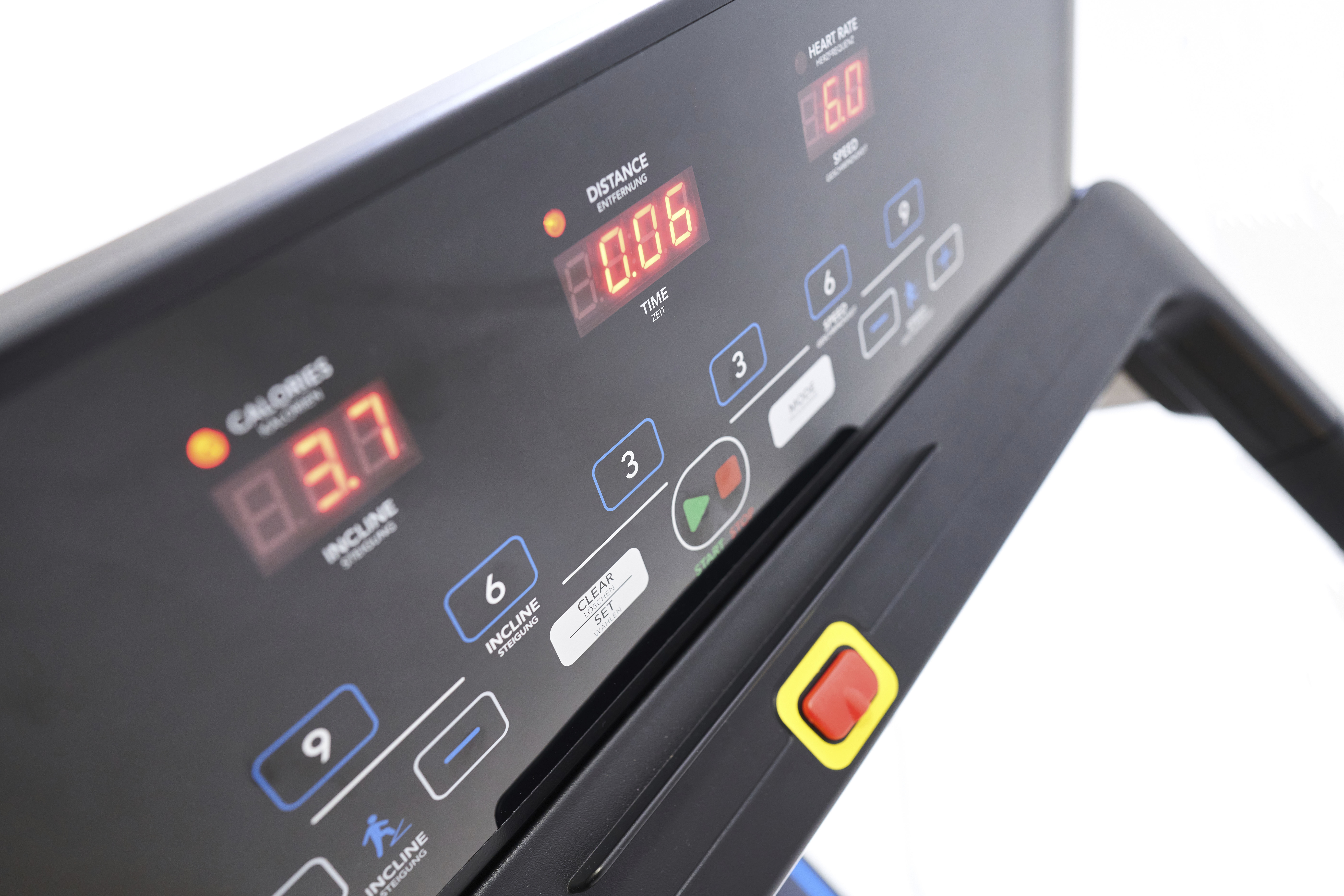 Primo piano del pannello di controllo di un tapis roulant che mostra tempo, distanza, calorie, velocità e impostazioni di inclinazione.