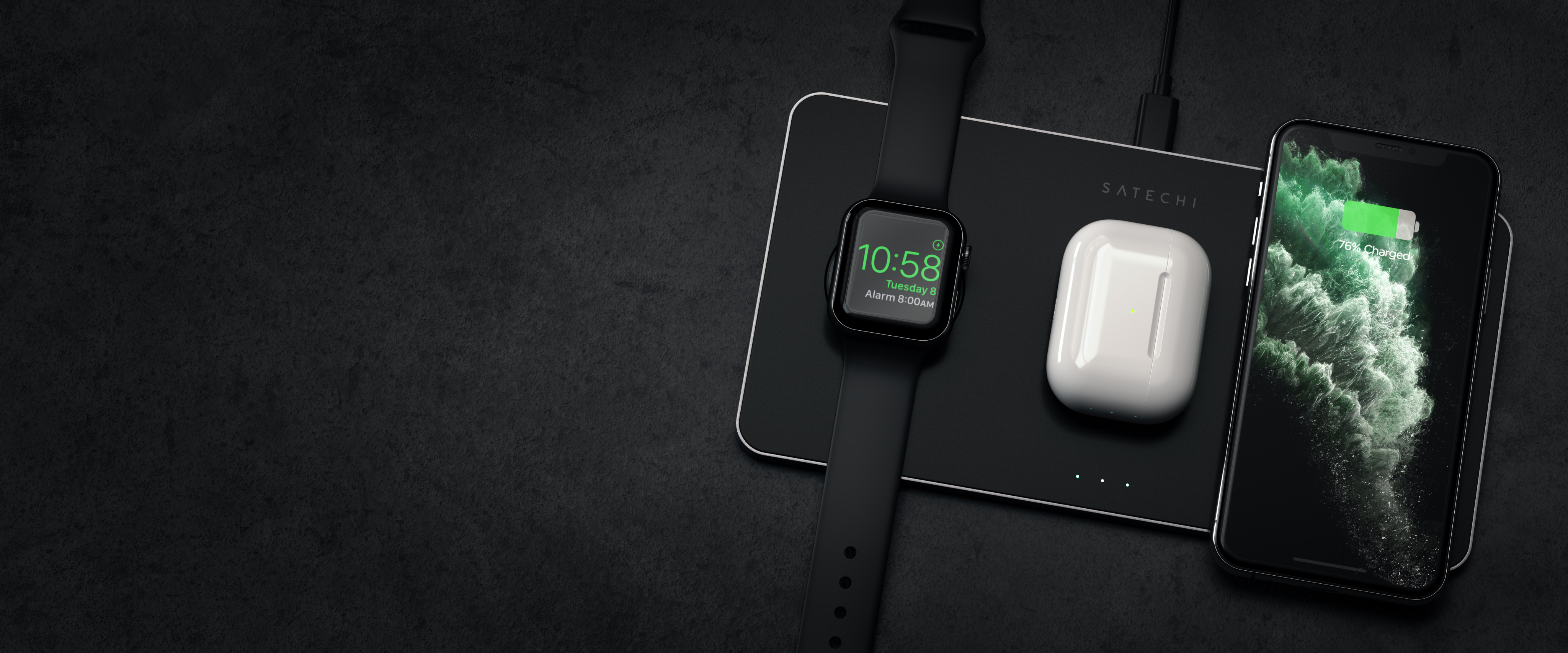 Un reloj inteligente, auriculares y un teléfono inteligente cargando en un cargador inalámbrico negro.