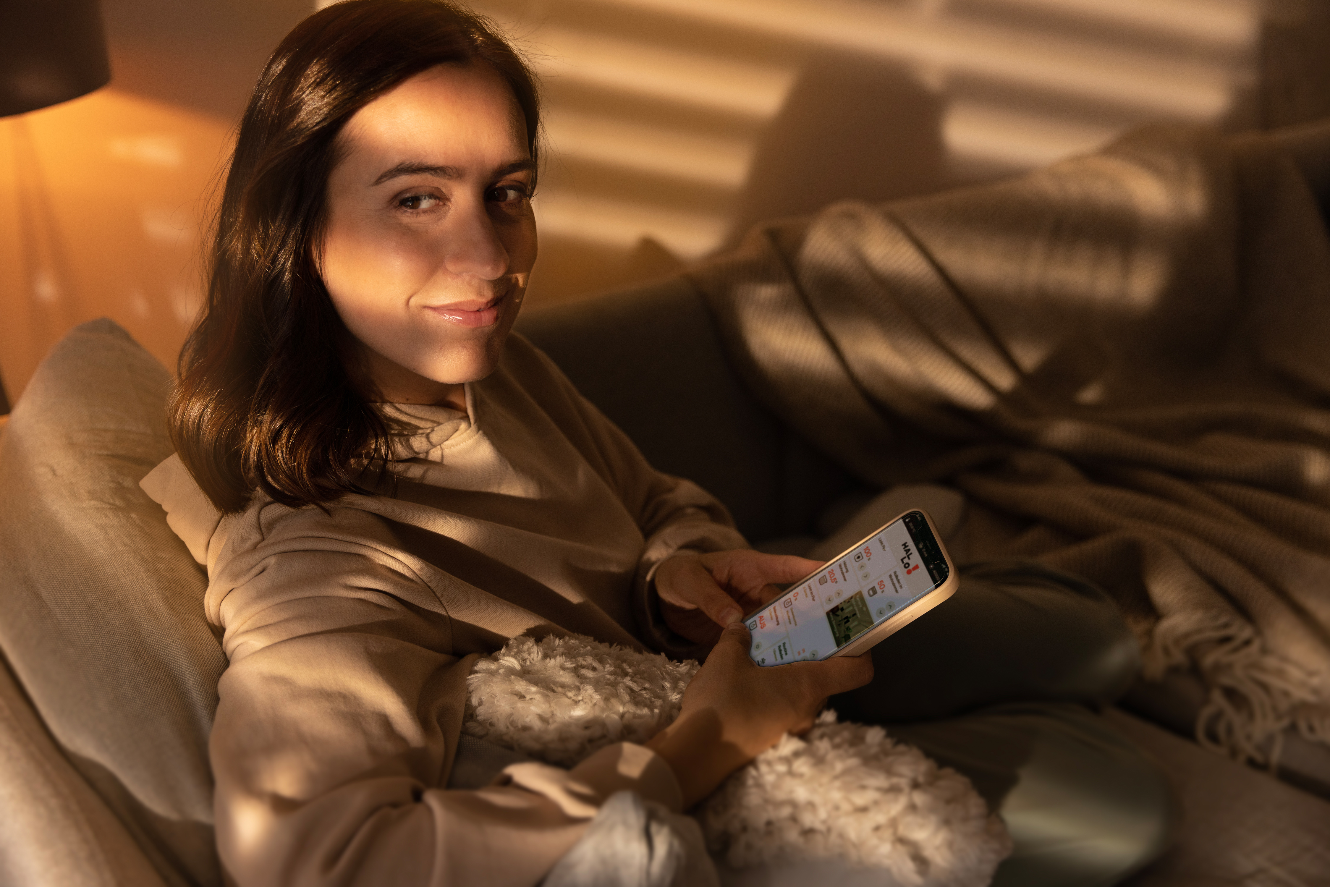 Eine Frau auf einem Sofa, die ein Telefon hält.