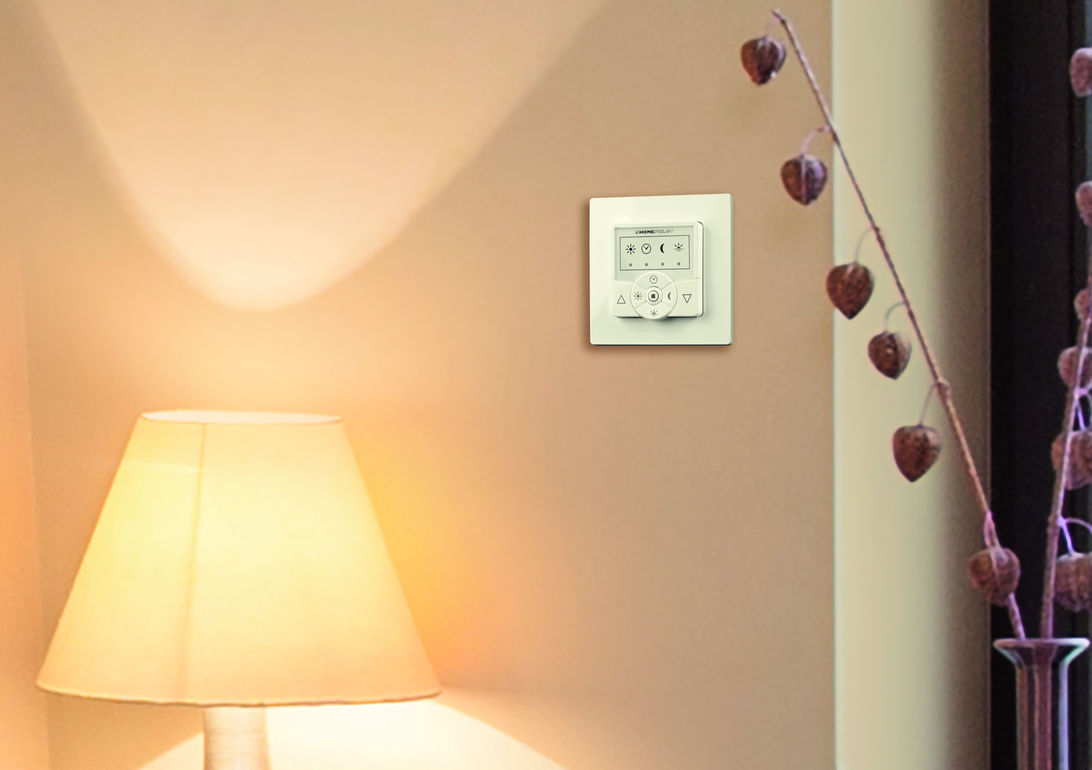 Weißes Bedienfeld an beigefarbener Wand. Eine Lampe und eine Pflanze im Vordergrund.