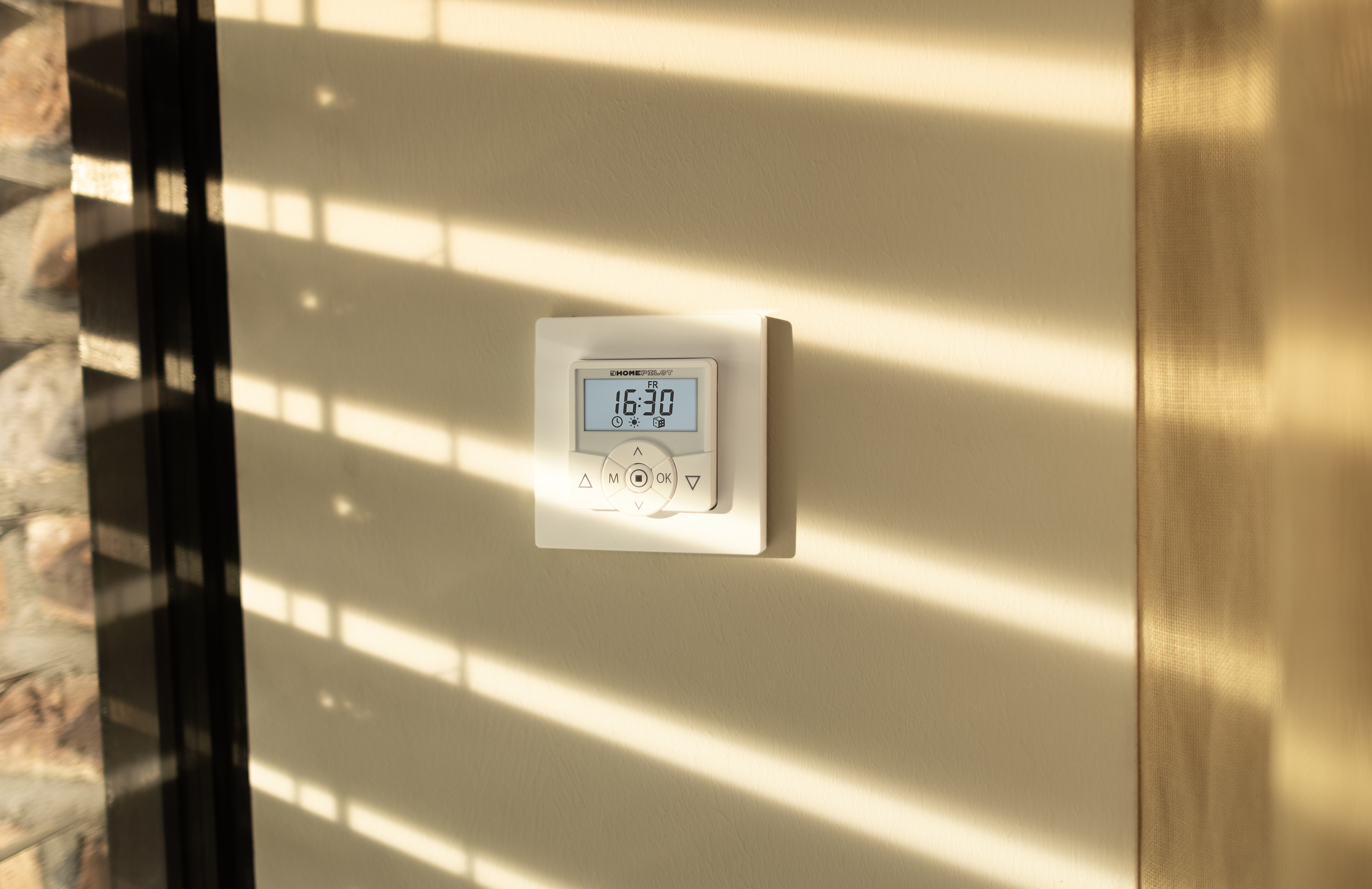 Thermostat an der Wand, mit Licht von Jalousien.