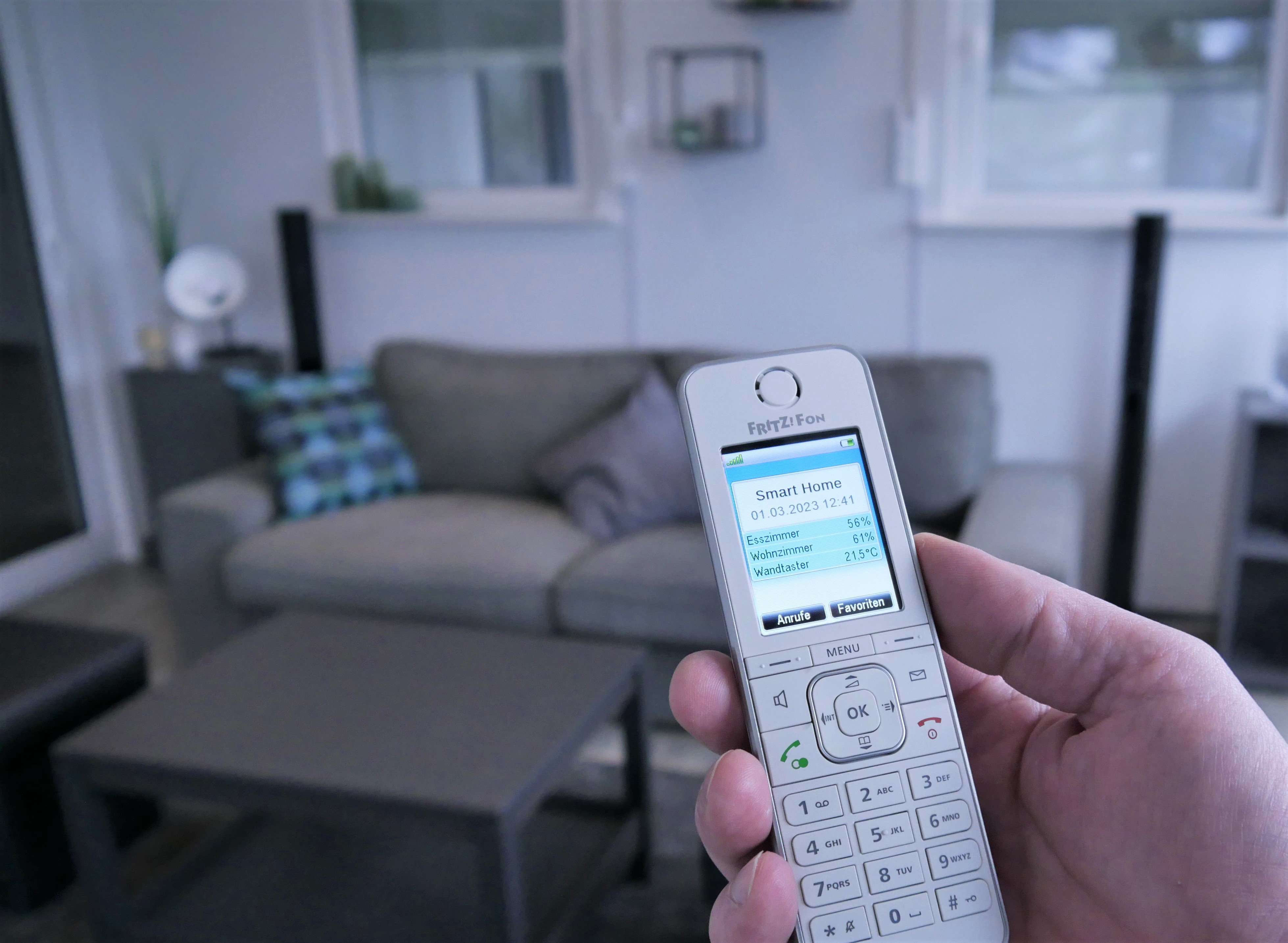 Hand hält Telefon, zeigt Smart-Home-Informationen.