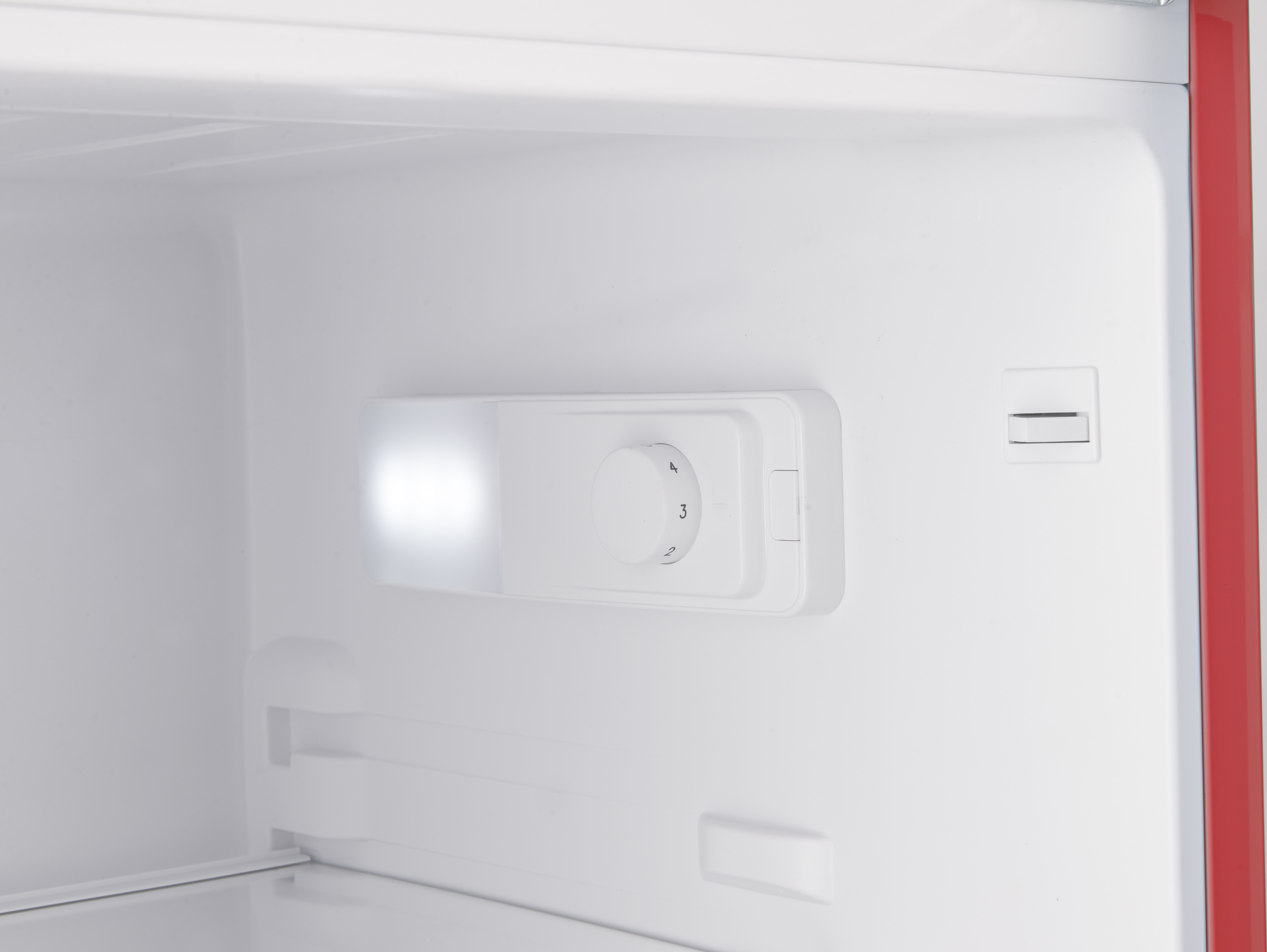 Innenraum eines Kühlschranks mit weißem Innenraum, Licht und Temperaturregler.