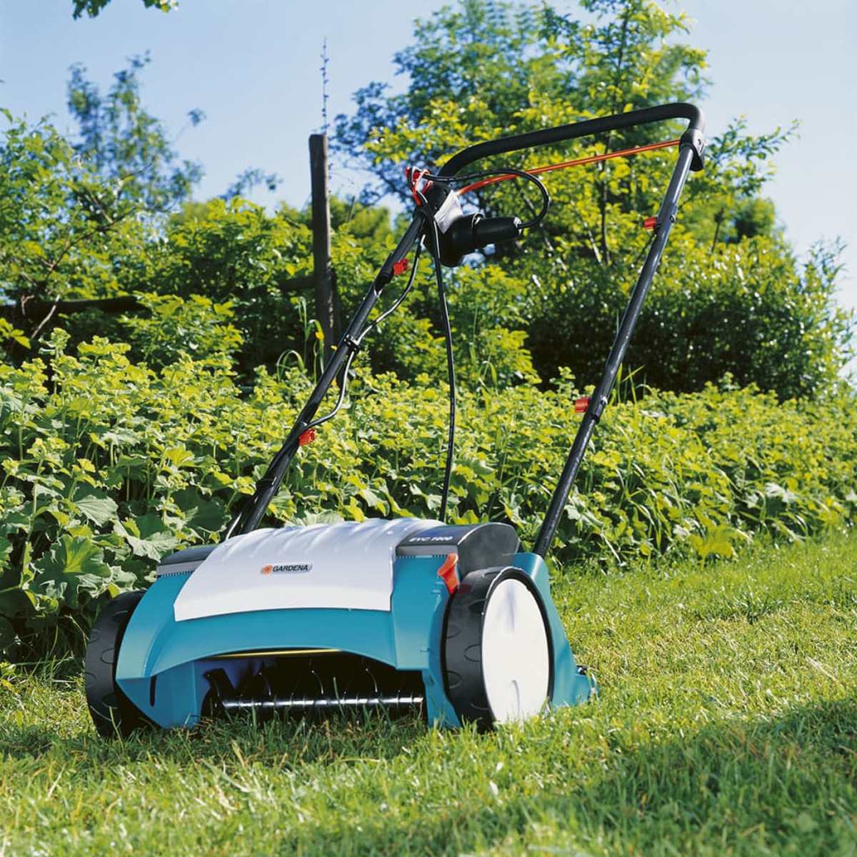 Tosaerba verde in un campo, corpo blu e bianco, ruote nere.