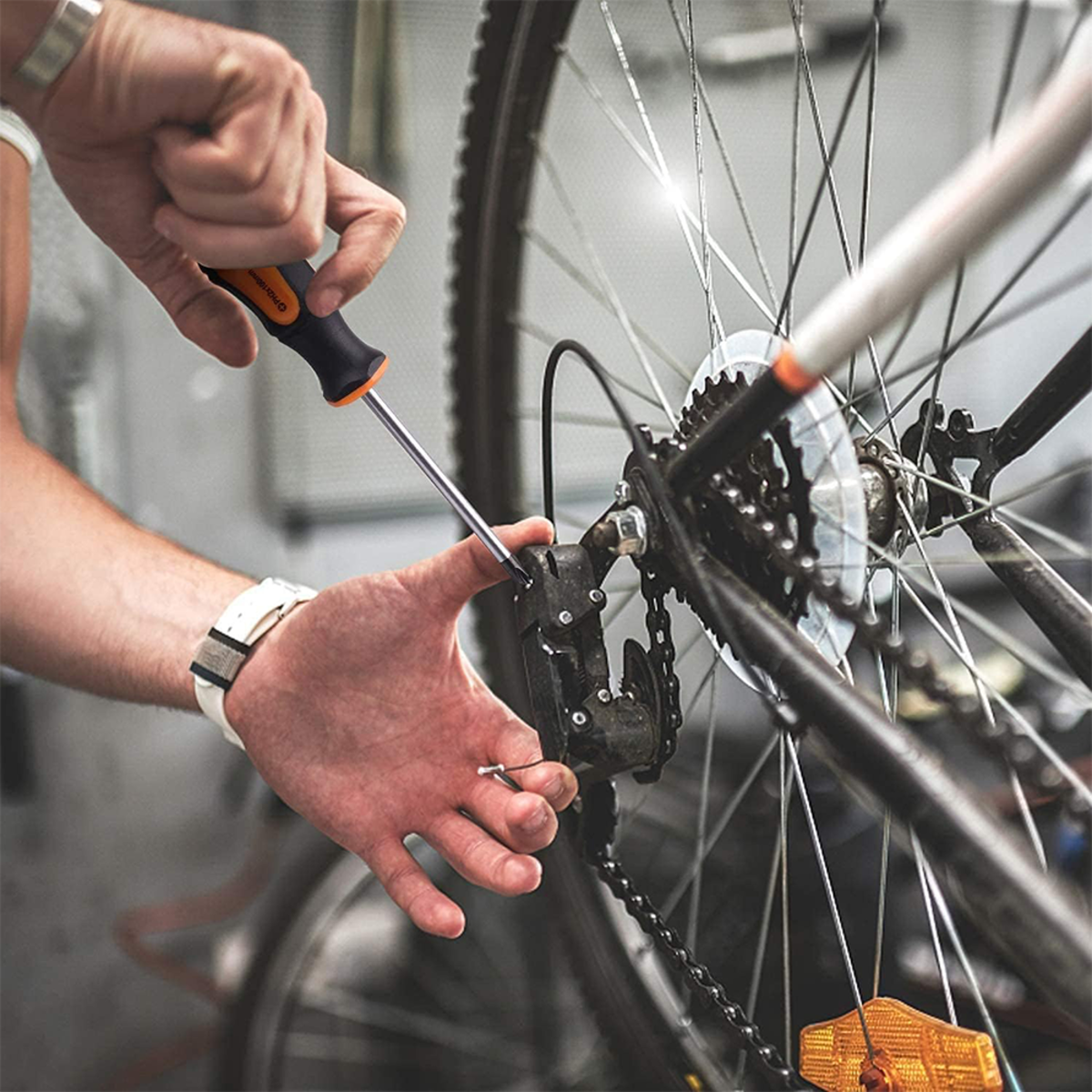 Una persona usando un destornillador para trabajar en una rueda de bicicleta.