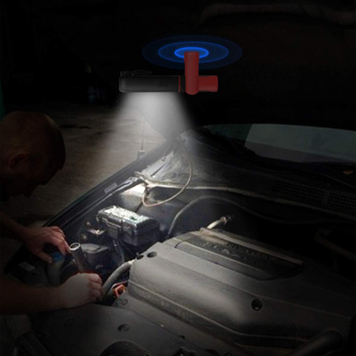 Mann arbeitet an einem Automotor, beleuchtet von einer roten und weißen Taschenlampe.
