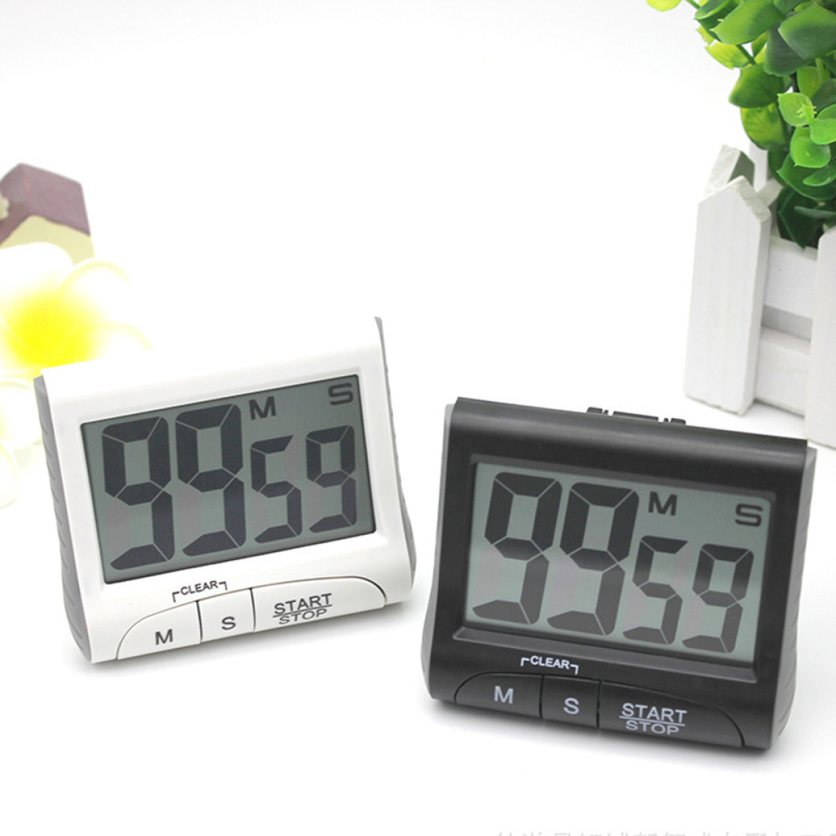 Zwei digitale Küchentimer, einer weiß, einer schwarz, beide zeigen 99:59. Knöpfe darunter: 'Löschen' und 'Start/Stop'.