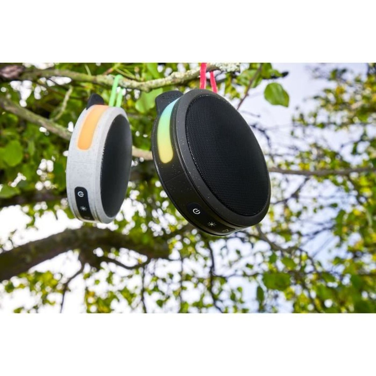 Dwa okrągłe czarne głośniki wiszące na gałęziach, ze światłami i przyciskami.