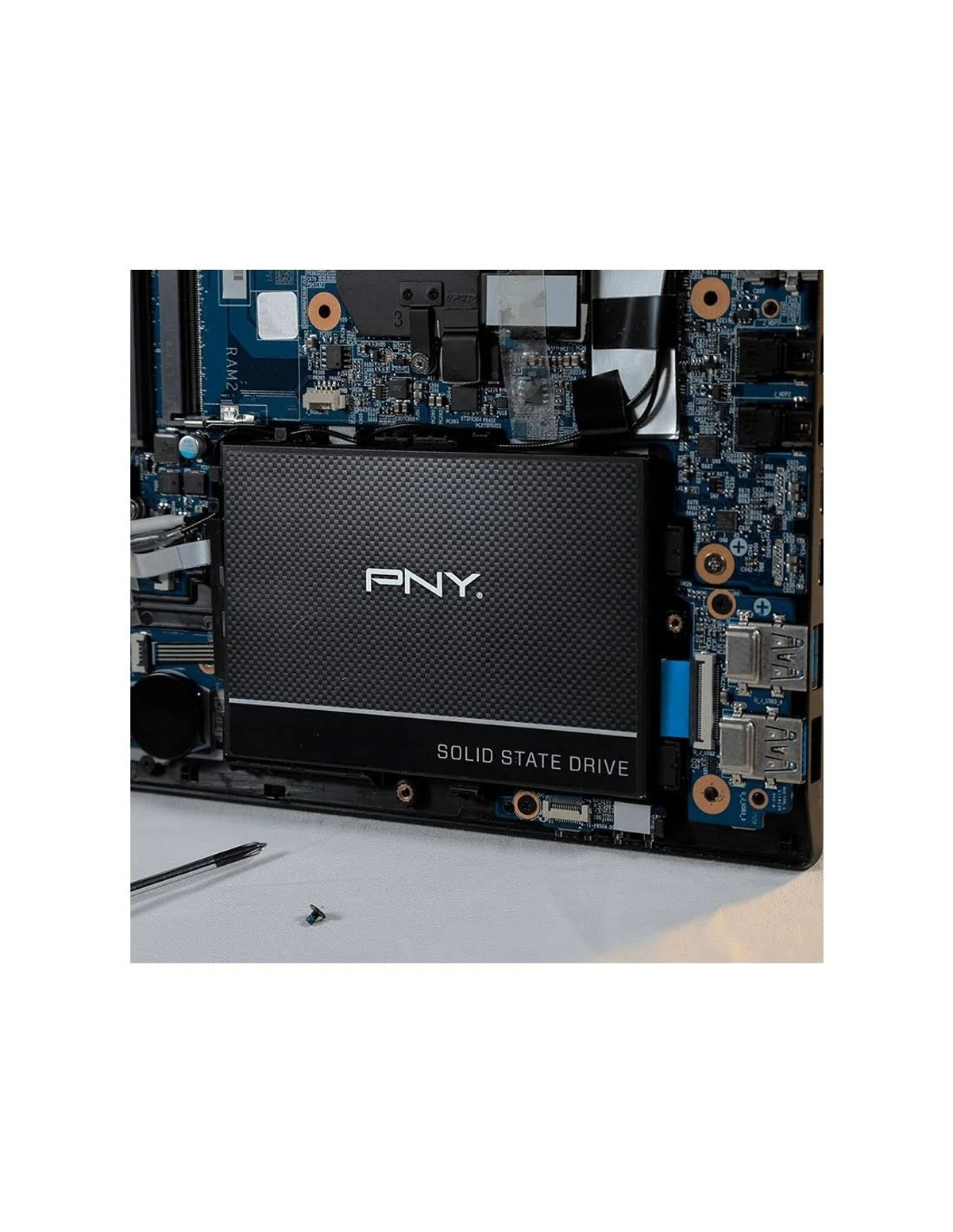 Wnętrze laptopa, pokazujące czarny dysk SSD, otoczony niebieskimi obwodami i elementami.