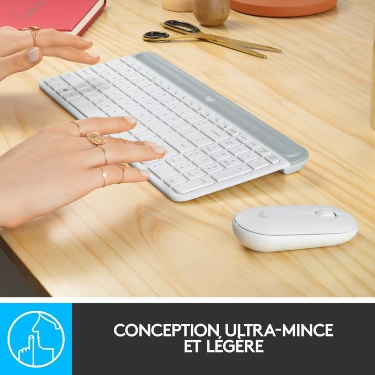 Ręce używają białej klawiatury i myszy na drewnianym stole, widoczne nożyczki.