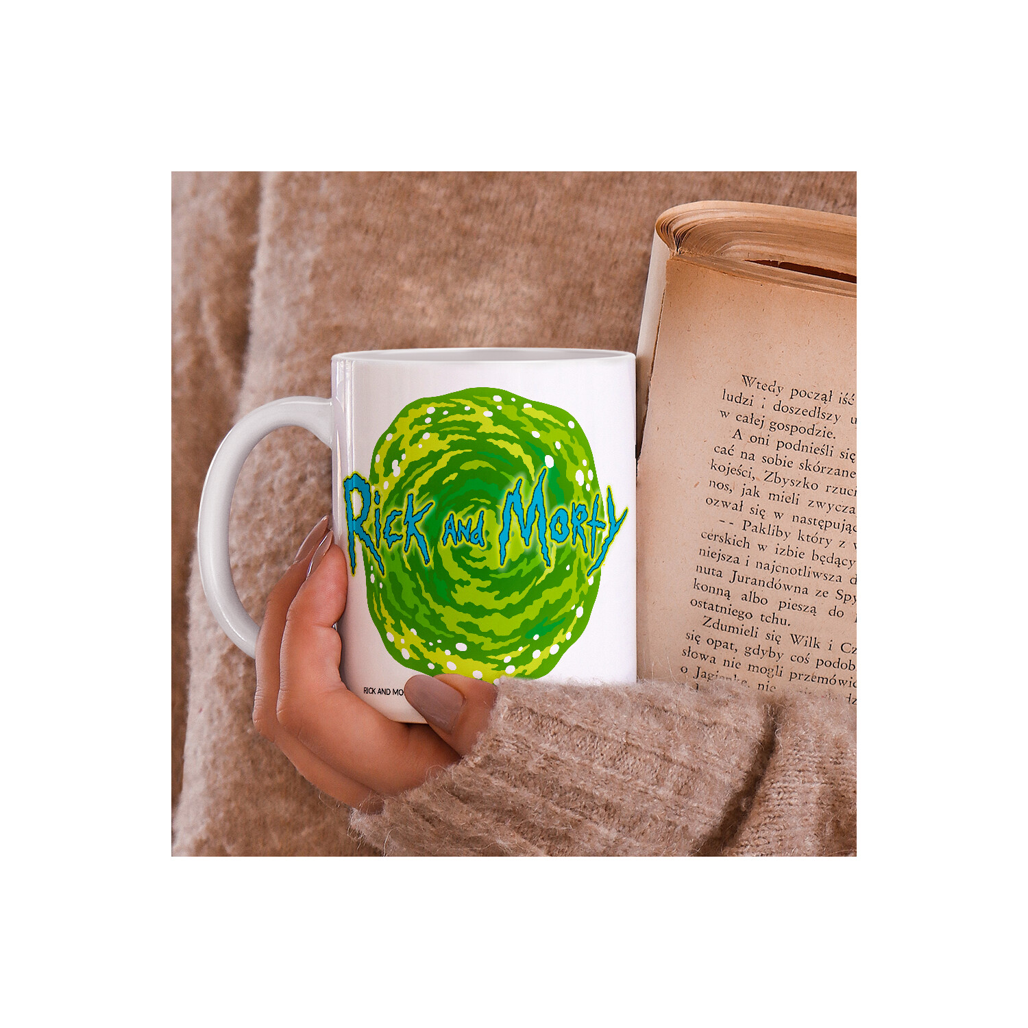 Hand hält eine weiße Tasse mit Rick and Morty Design, im Hintergrund ein Buch.