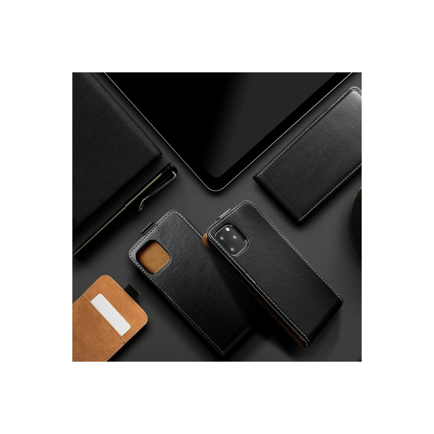 Una collezione di custodie per telefono in pelle nera, una penna e un tablet su una superficie scura. Dettagli di cucitura bianchi.