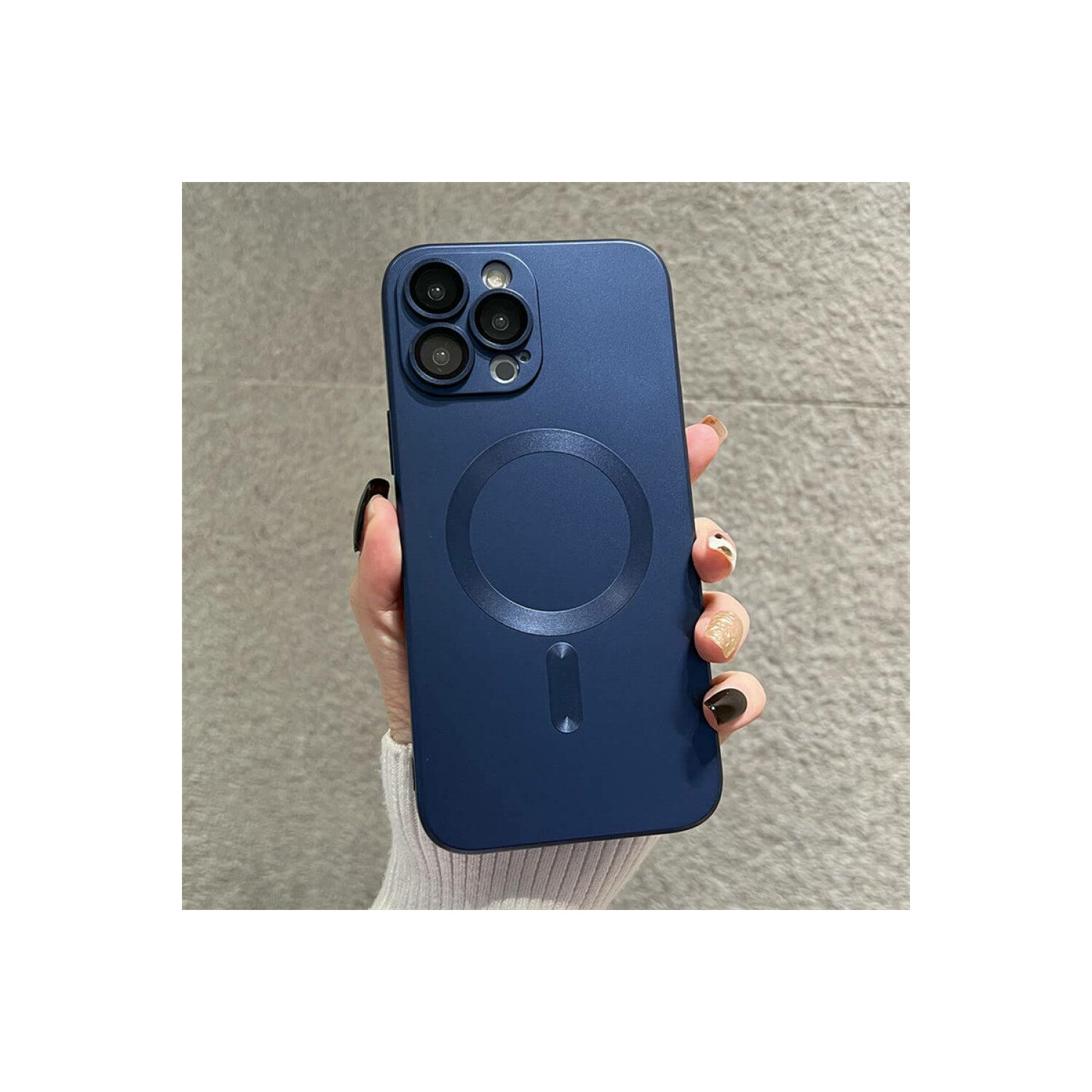 Una mano che tiene una custodia blu navy con un design MagSafe circolare, ripresa ravvicinata.