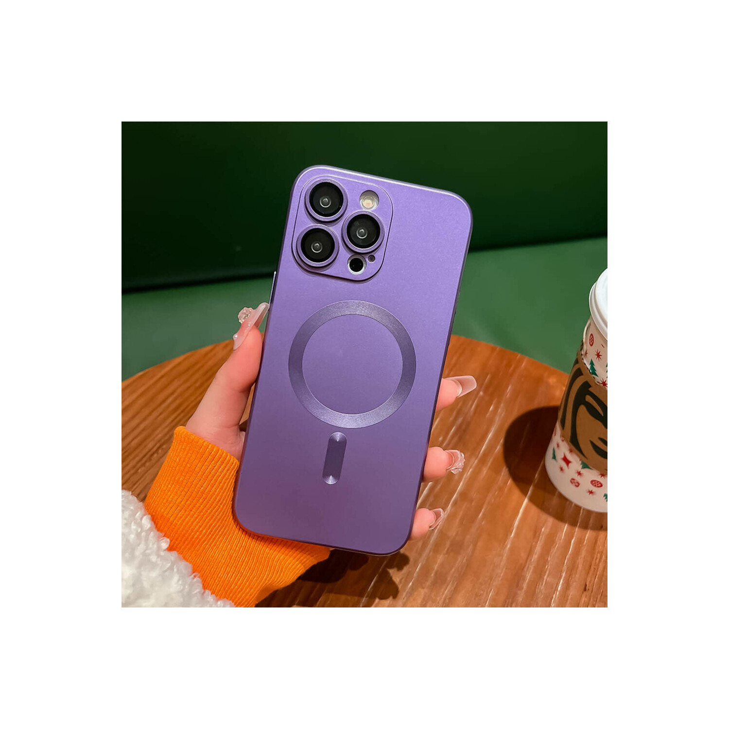 Mano che tiene una custodia viola con ritagli per la fotocamera e un design circolare su un tavolo di legno.