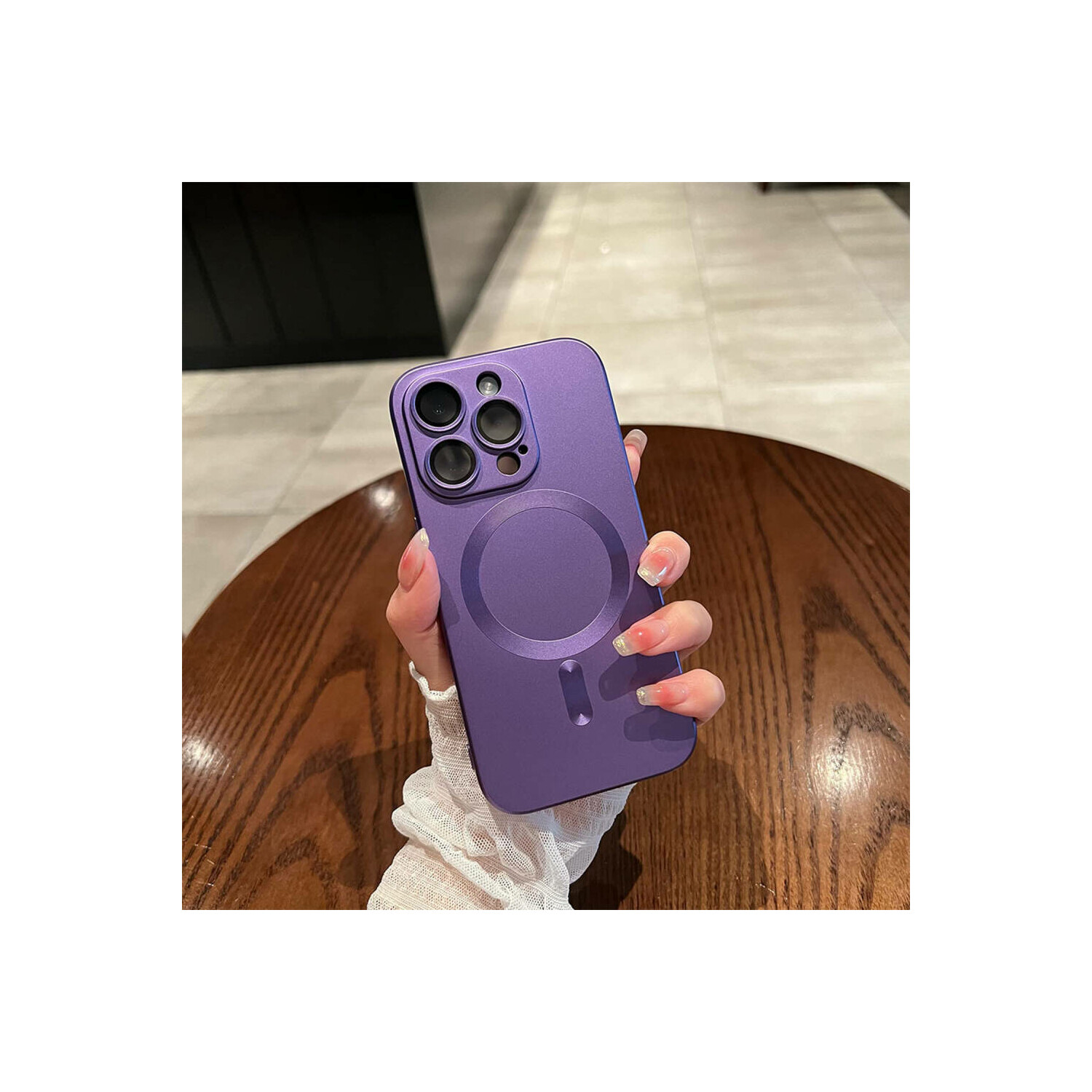 Una custodia per telefono viola con ritaglio per fotocamera tenuta da una mano su un tavolo di legno.