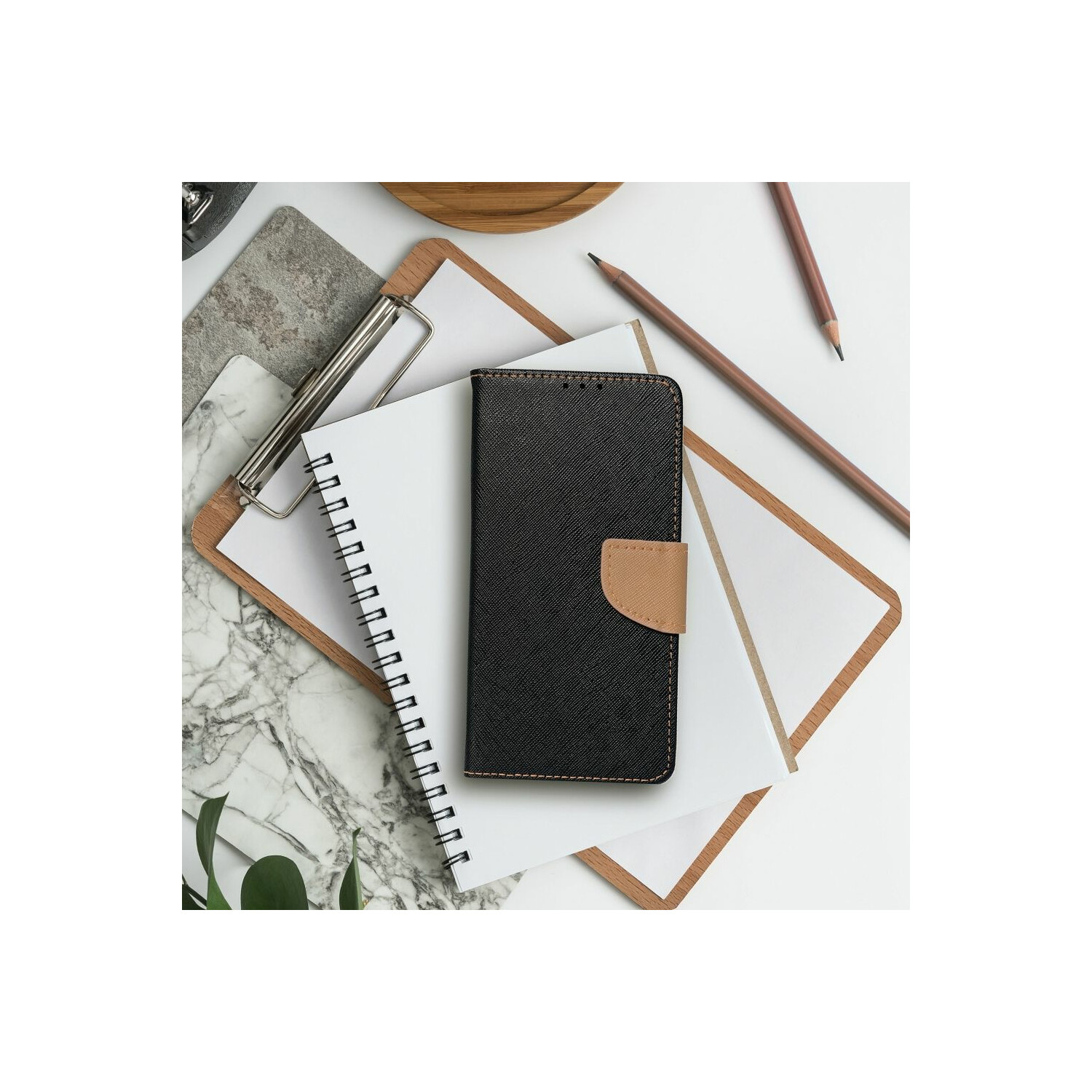 Quaderno, appunti, matite e una custodia per telefono su una superficie bianca.
