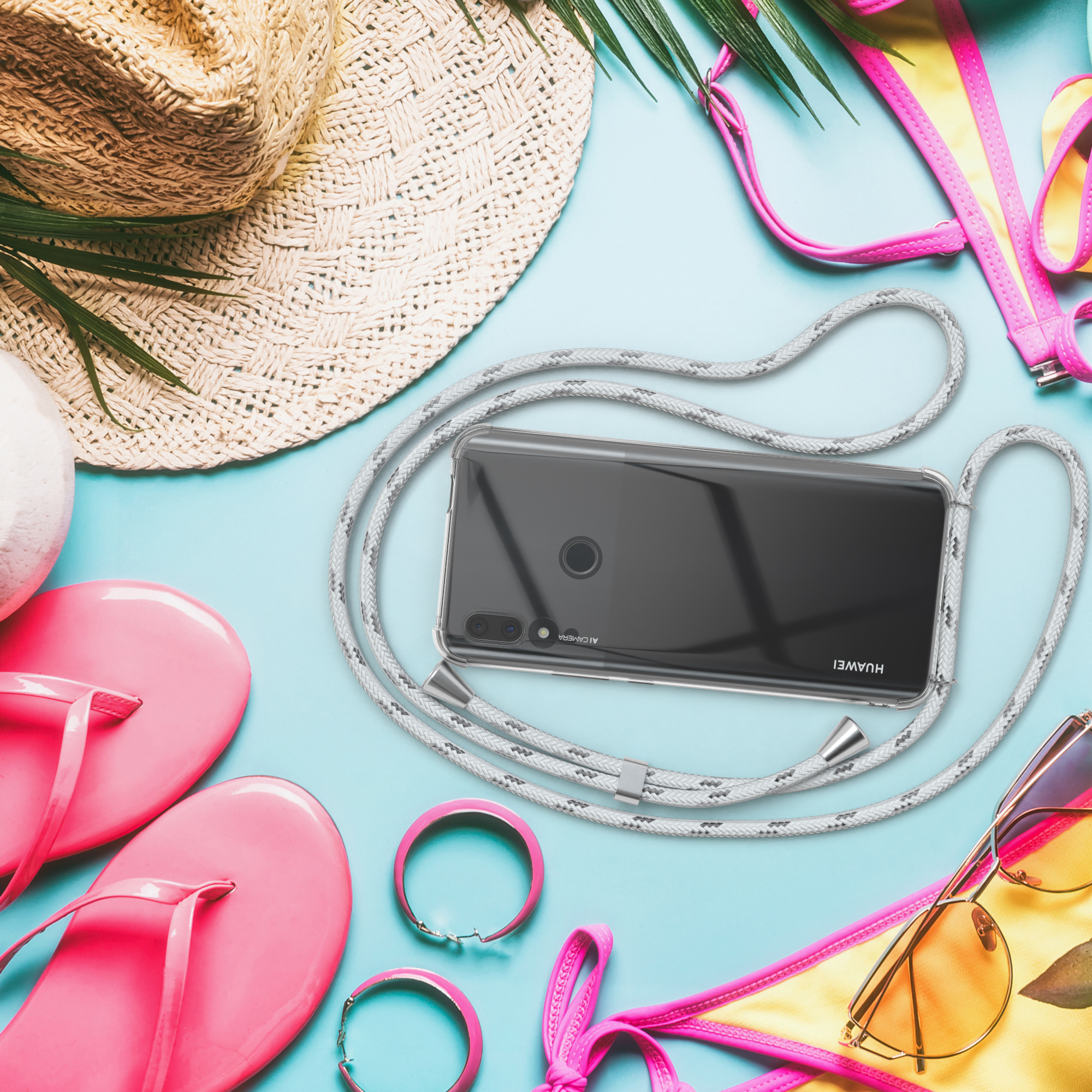 Ein Telefon mit grauem Kordelband, umgeben von Strandartikeln.