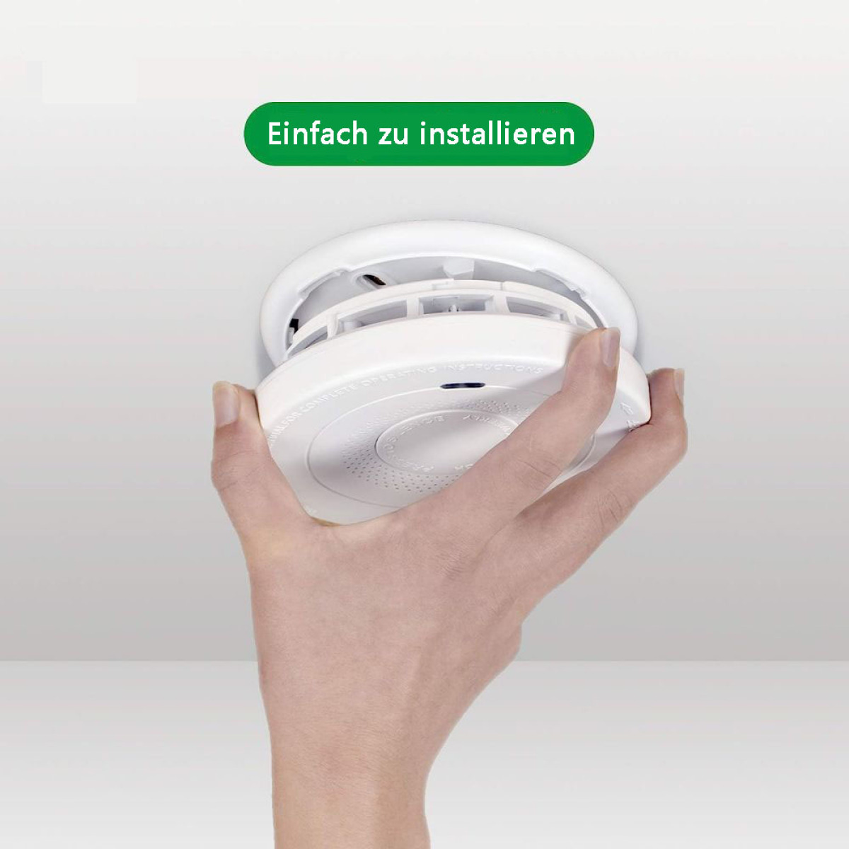 Hand installiert einen weißen Rauchmelder an einer Decke.