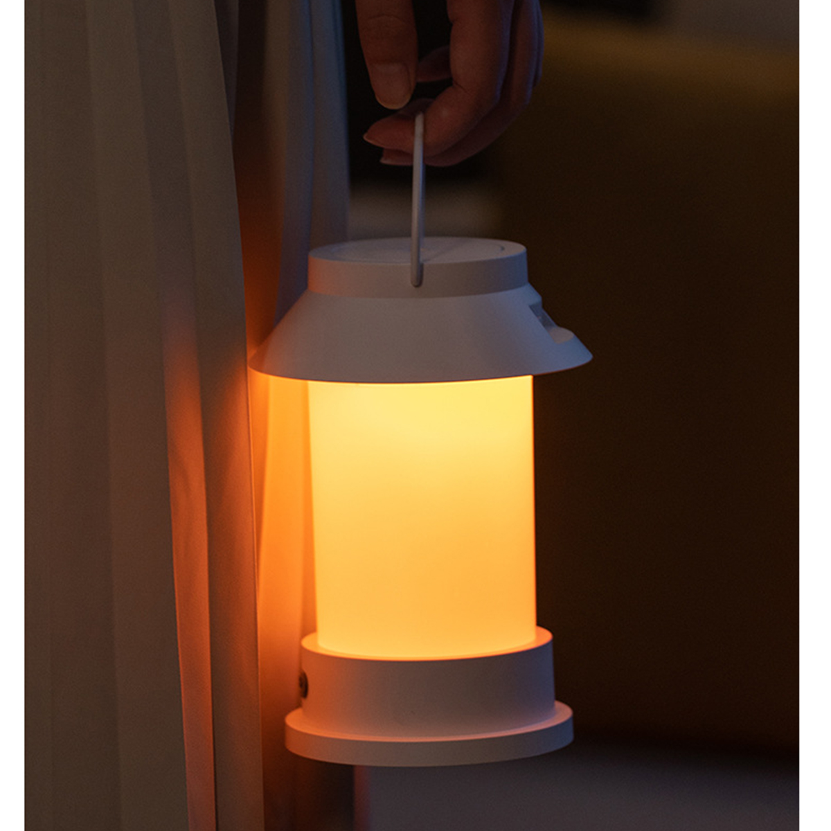 Eine weiße Laterne mit orangefarbenem Licht, die von einer Hand gehalten wird. Der Hintergrund ist unscharf.