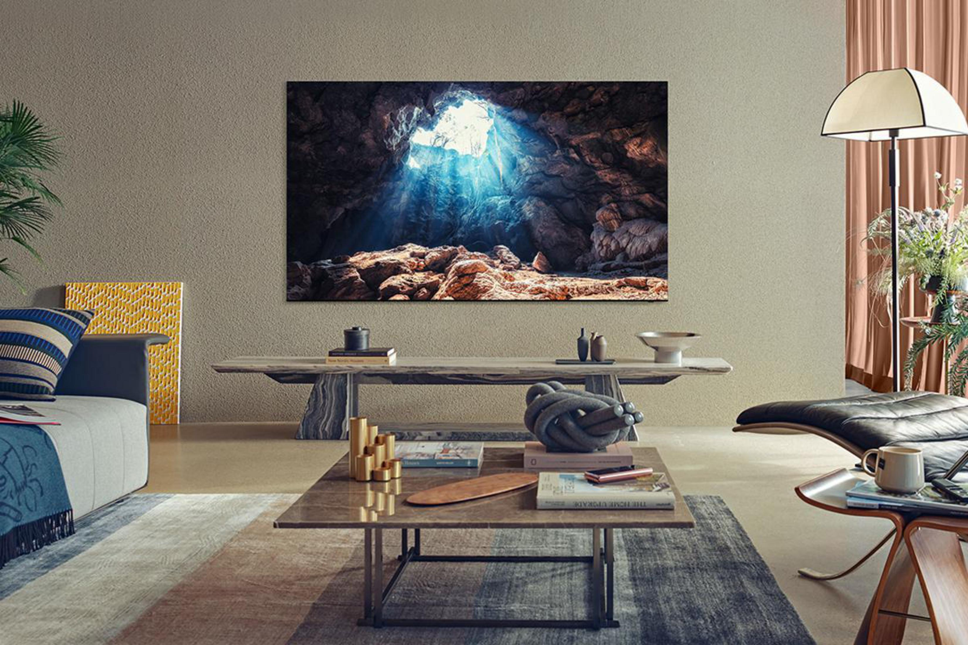 Salon z dużym telewizorem wyświetlającym scenę z jaskinią. Na pierwszym planie stolik kawowy i sofa.