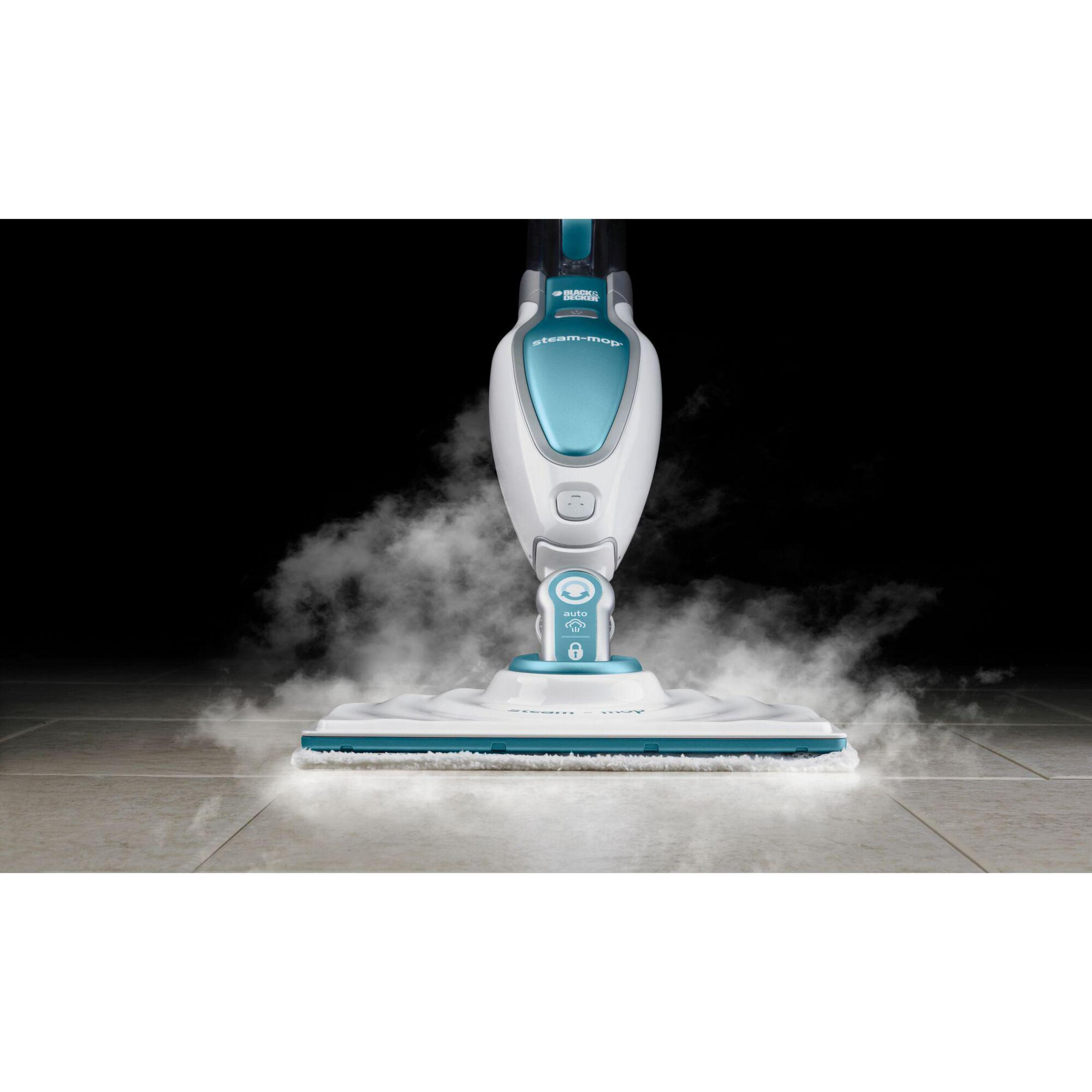 Mop parowy czyszczący kafelkową podłogę, wytwarzający parę. Biała i turkusowa głowica mopa na czarnym tle.