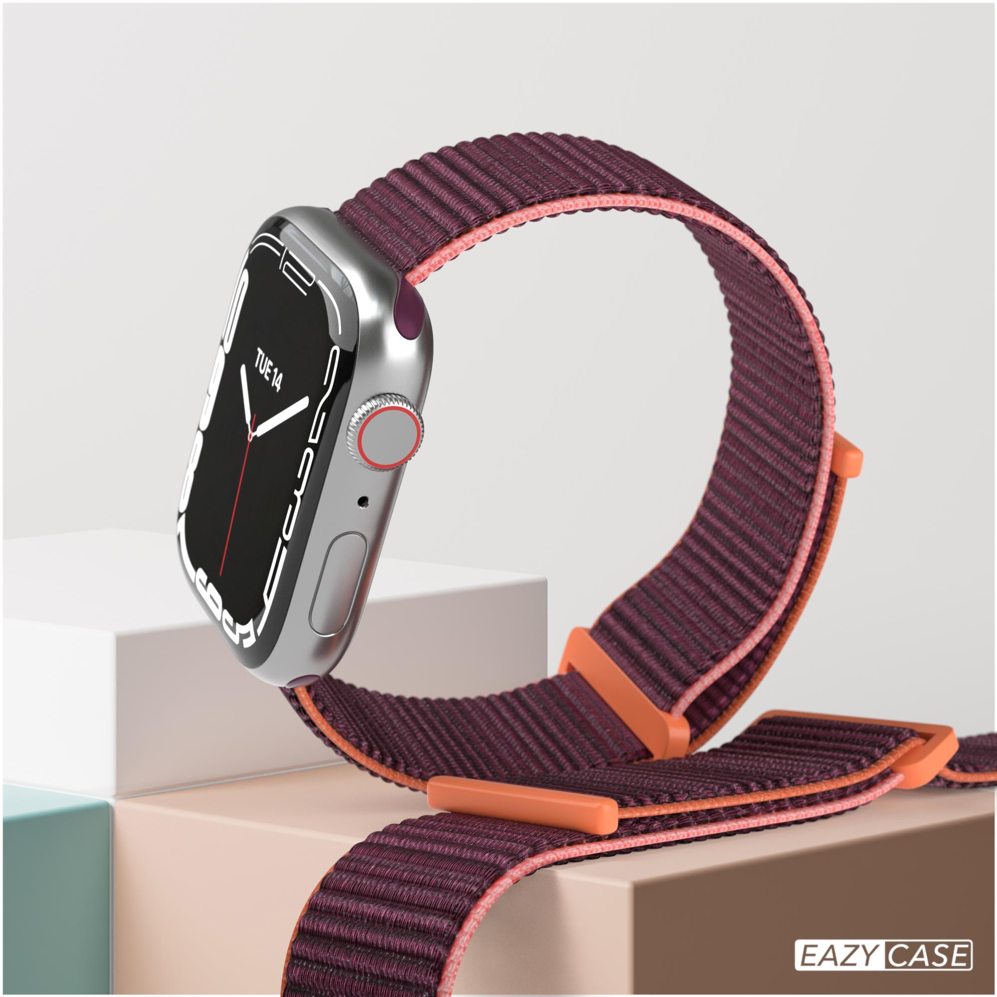 Apple Watch mit weinrotem Armband, auf weißer Oberfläche. Orangefarbene Banddetails. Beiger Hintergrund.